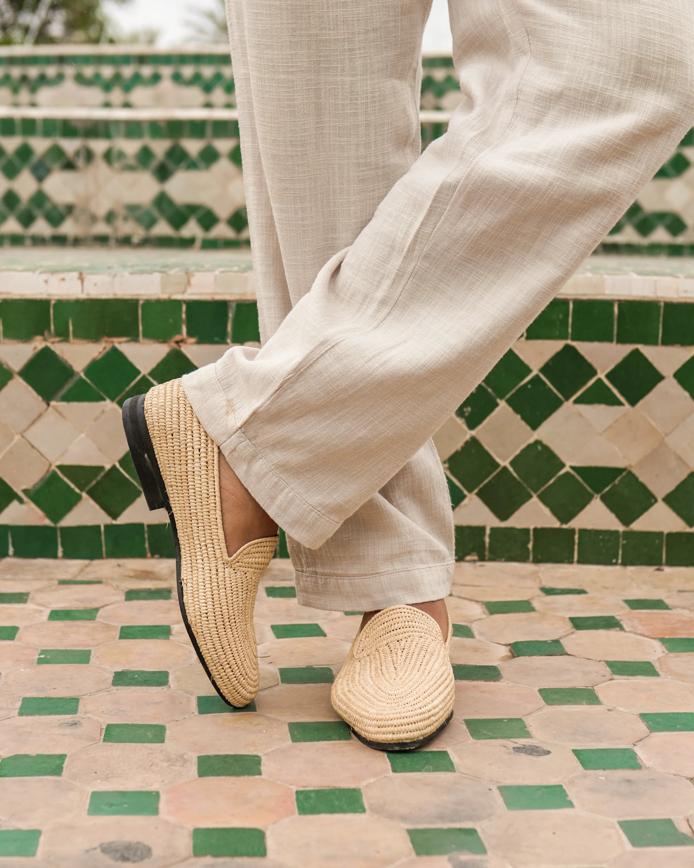 Person wearing beige espadrilles on a green and beige tiled floor.