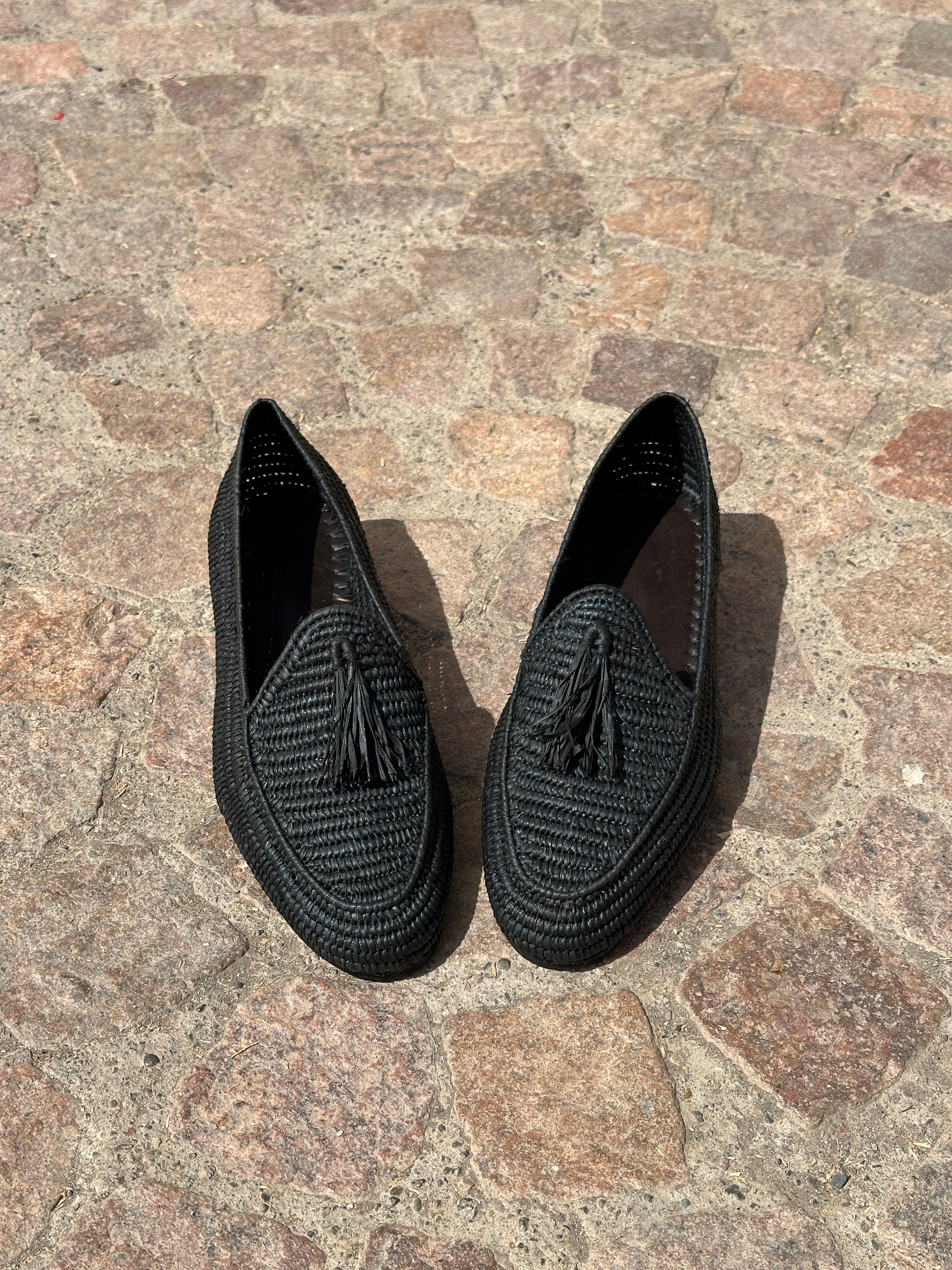 Two black slippers on a stone surface