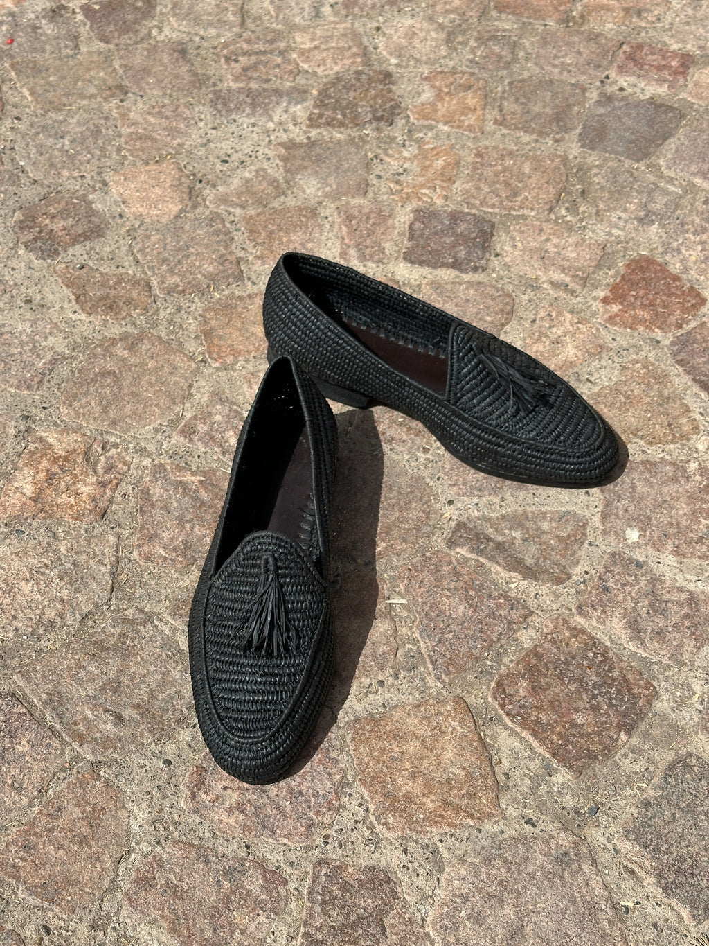 Pair of black loafers on a stone pavement
