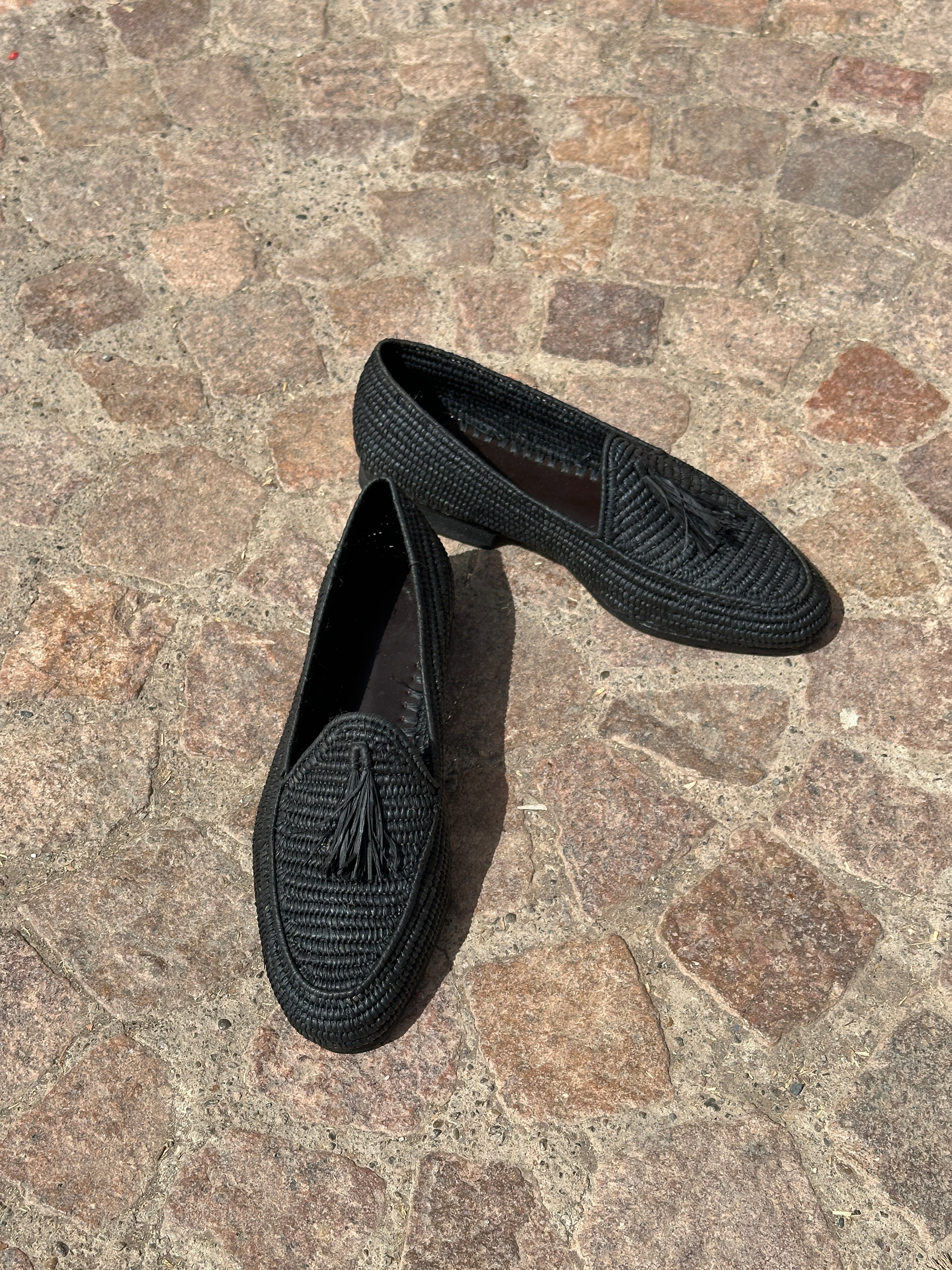 Pair of black loafers on a stone pavement