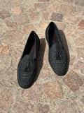Pair of black raffia loafers on a stone pavement