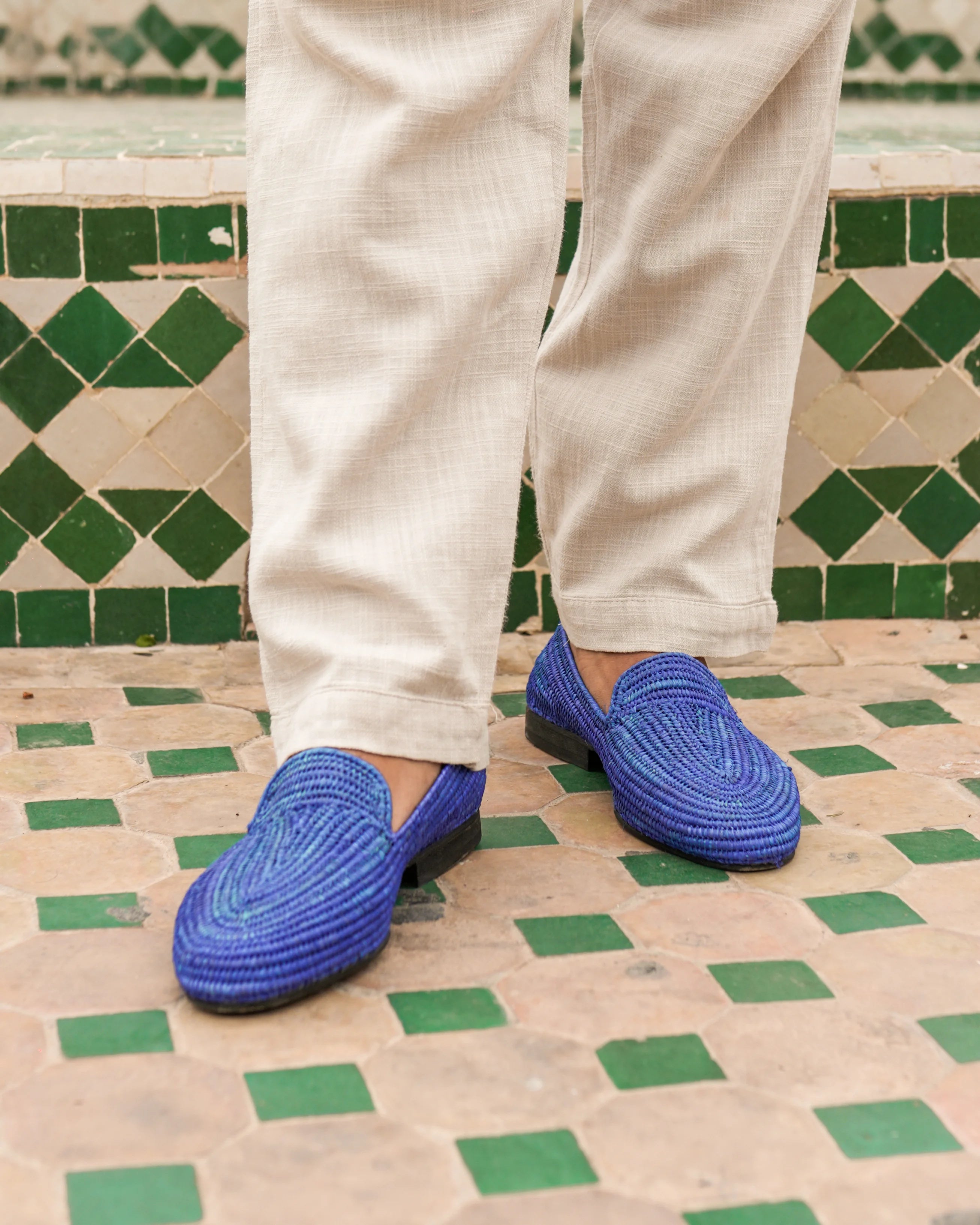 Person wearing blue loafers on a green and beige tiled floor