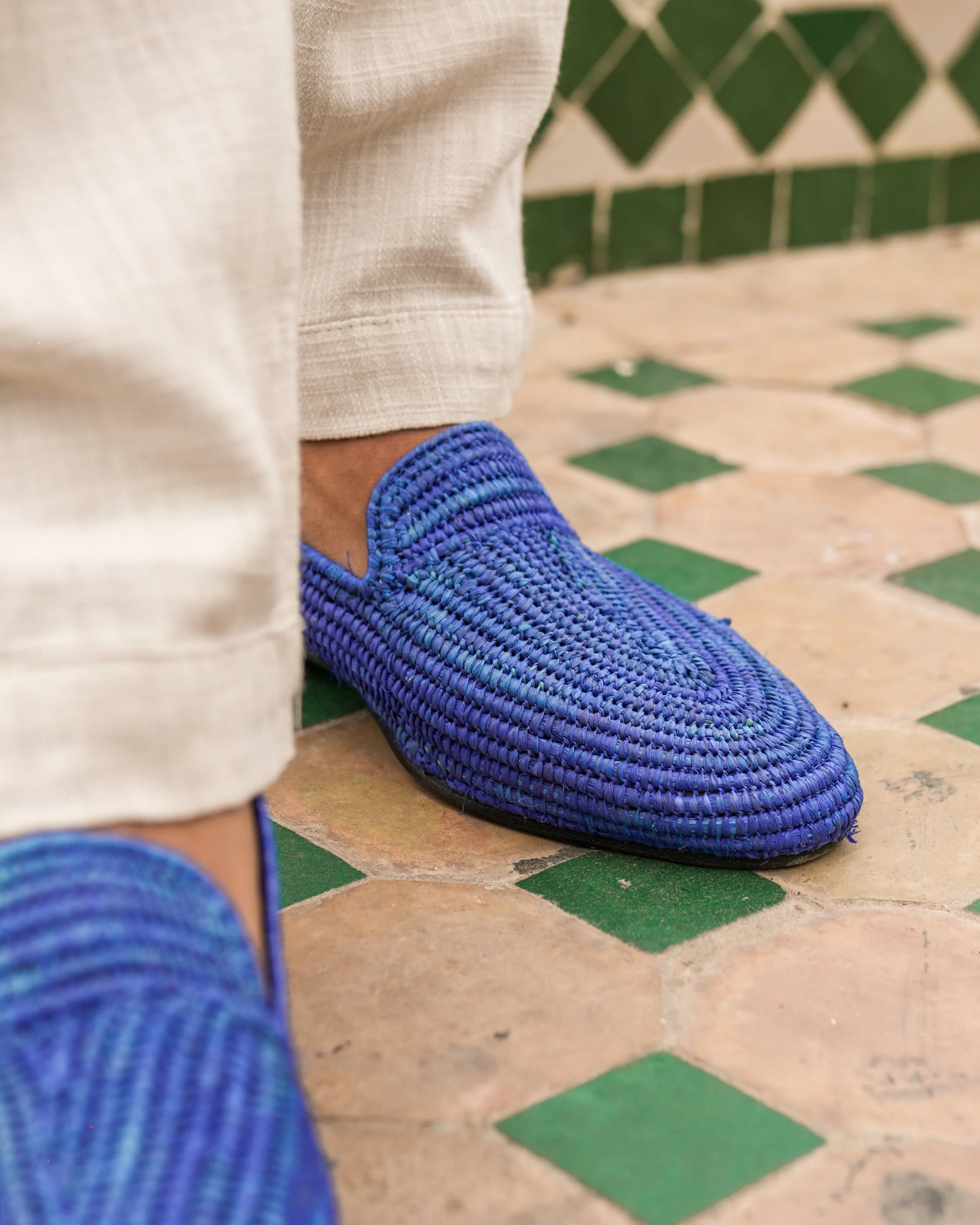 Blue woven shoes worn on a patterned floor