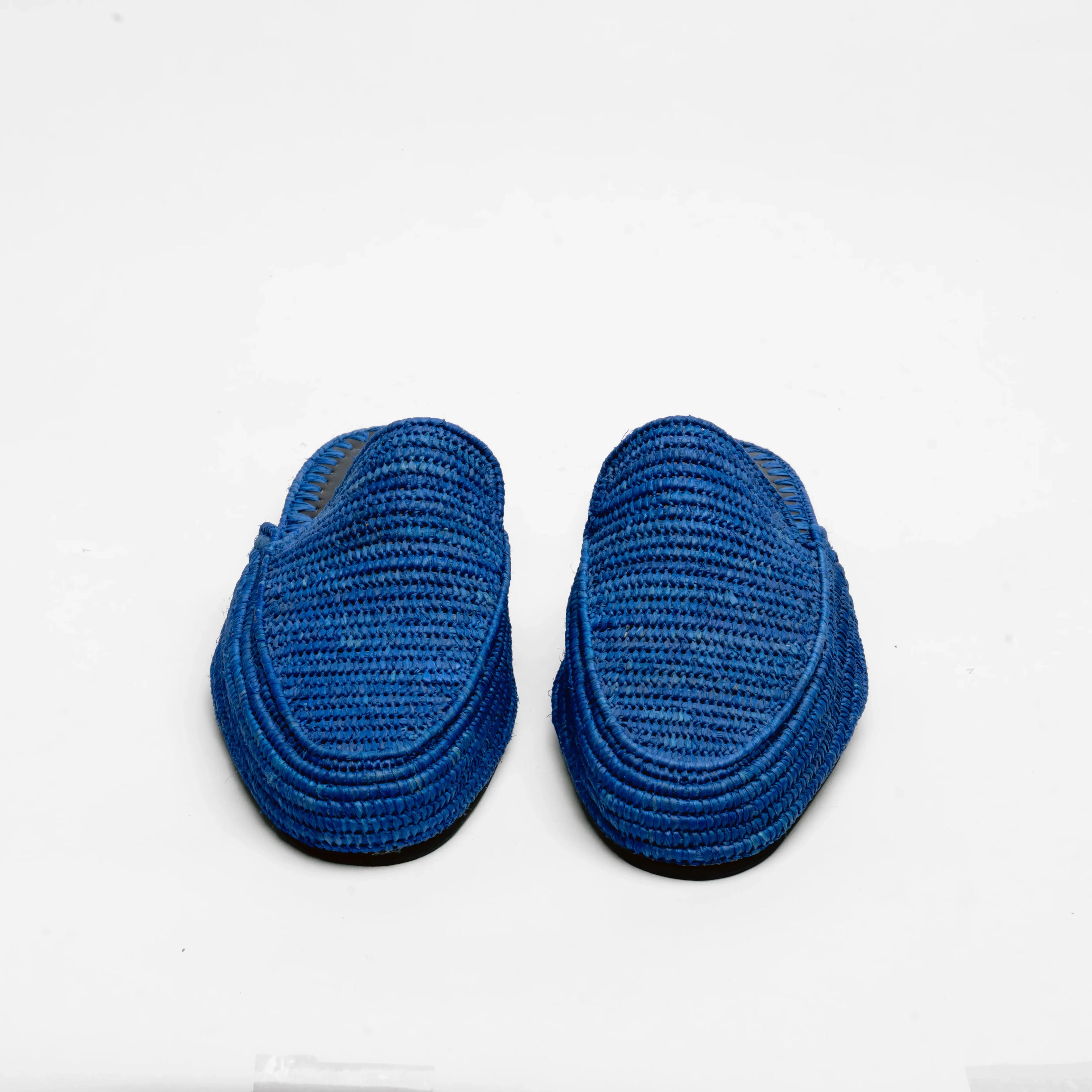 A pair of blue woven slip-on mule with a textured braided upper and a black outsole, shown from a top-down view on a white background.