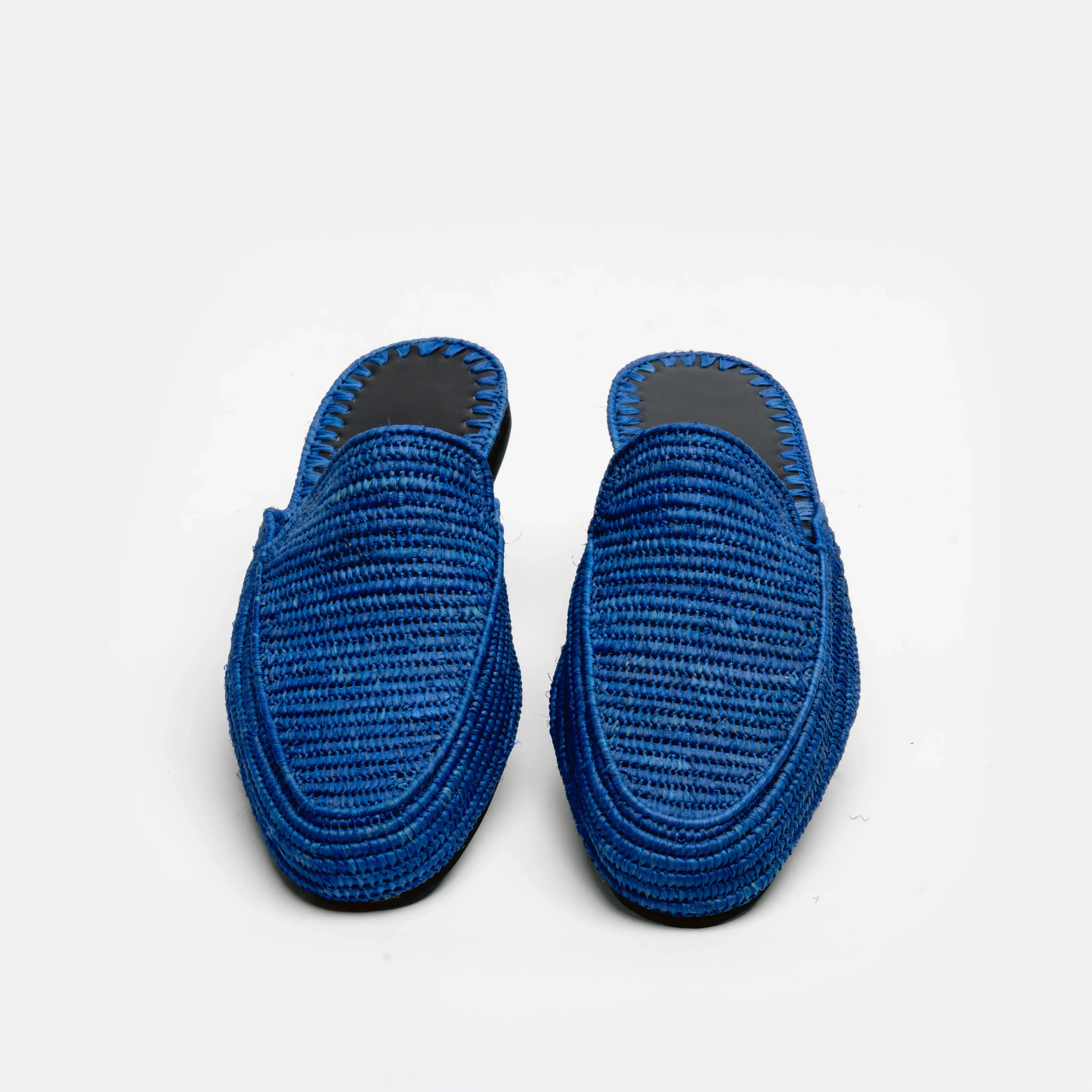 A pair of blue woven slip-on mule shoes with black soles, displayed side-by-side on a clean white background.