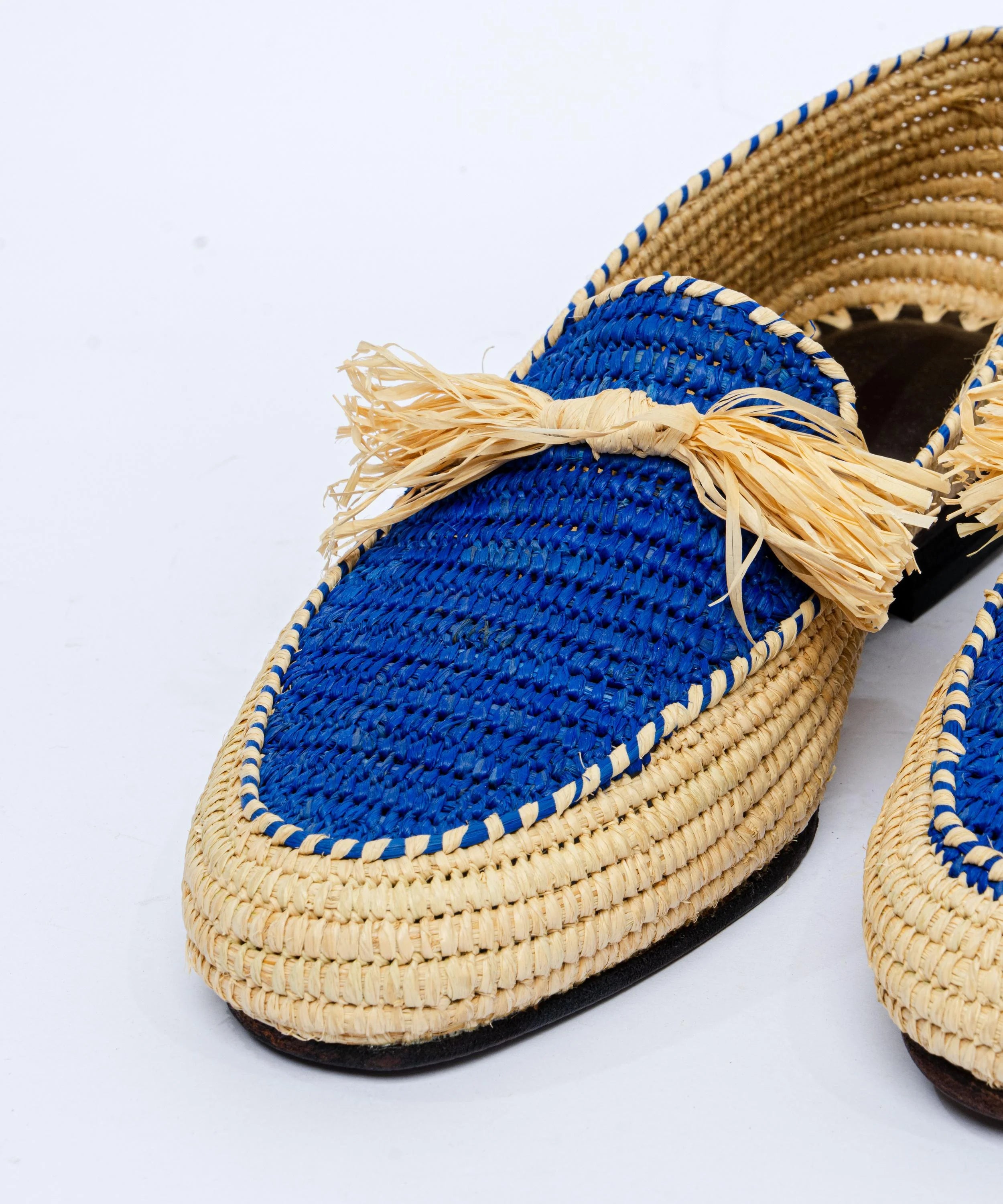 Woven shoes with blue soles and beige straps on a light gray background