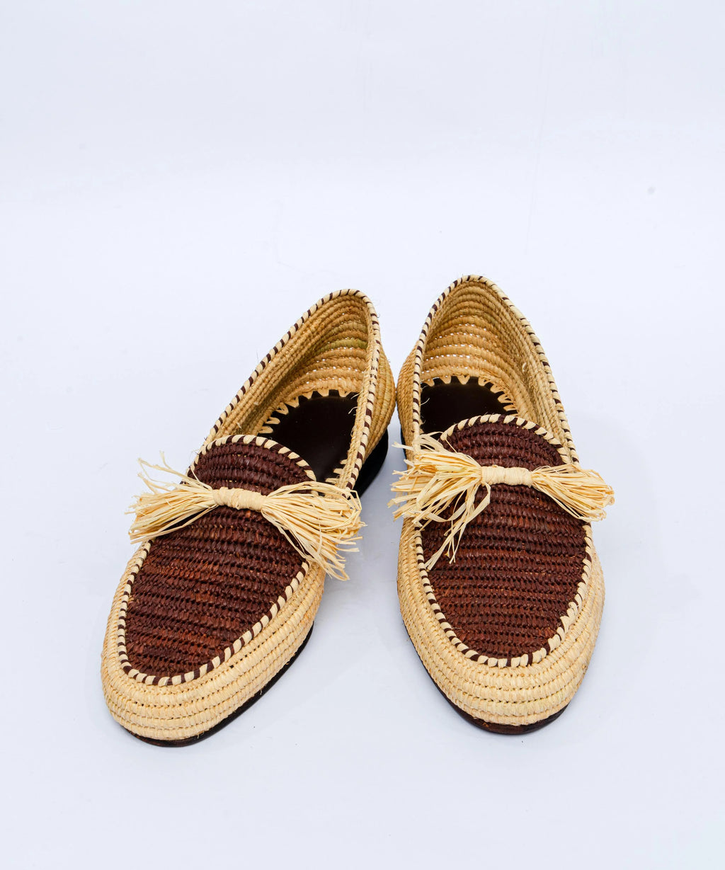 Pair of woven shoes with tassels on a light gray background