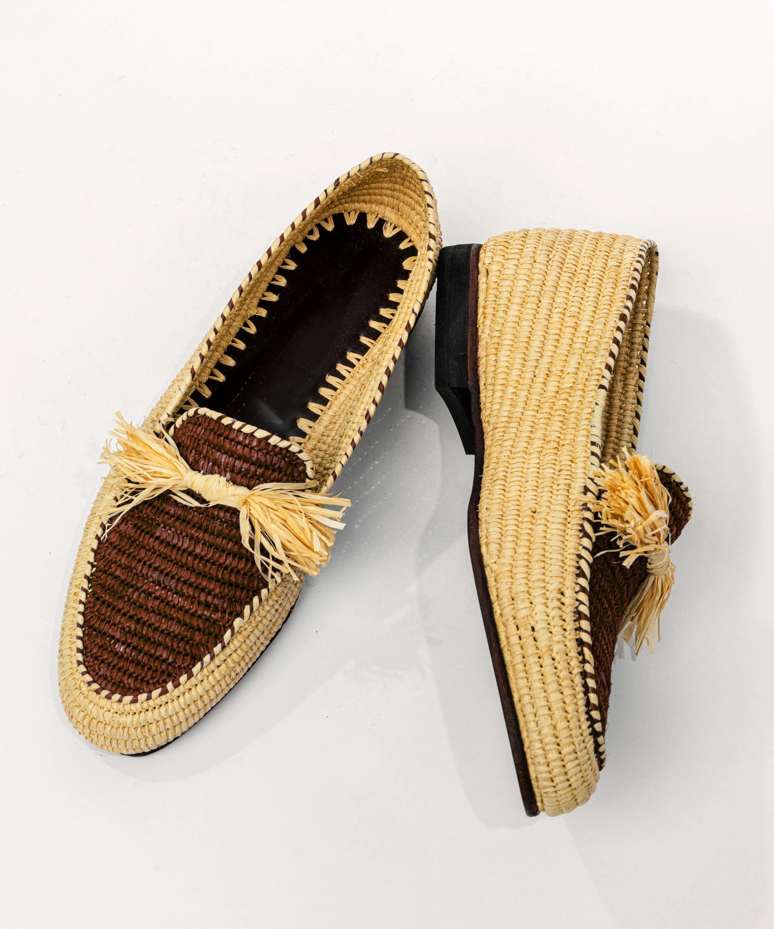 Pair of woven shoes with tassels on a white background