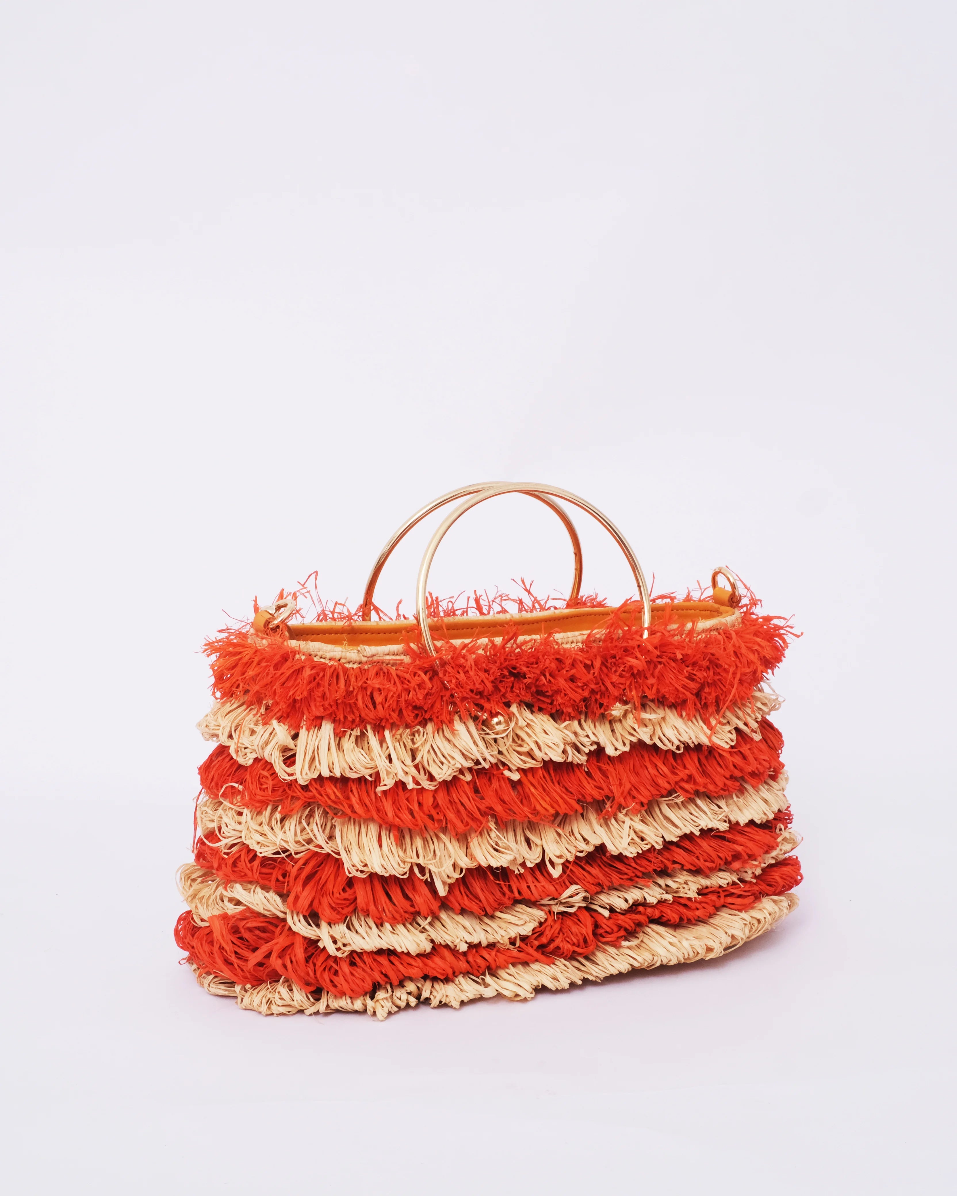 Stacked red and beige woven bags on a light gray background