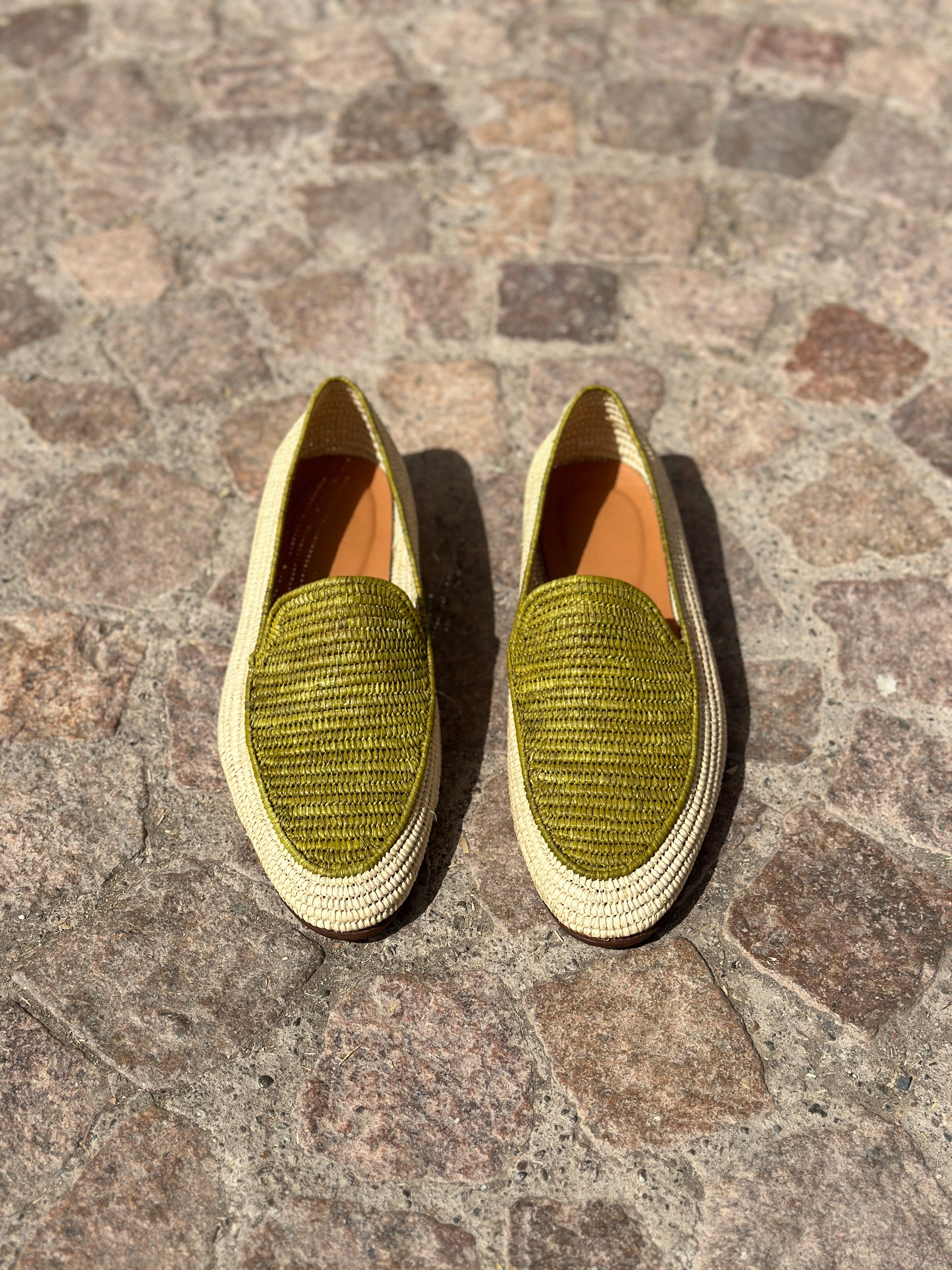 Pair of green woven shoes on a stone pavement