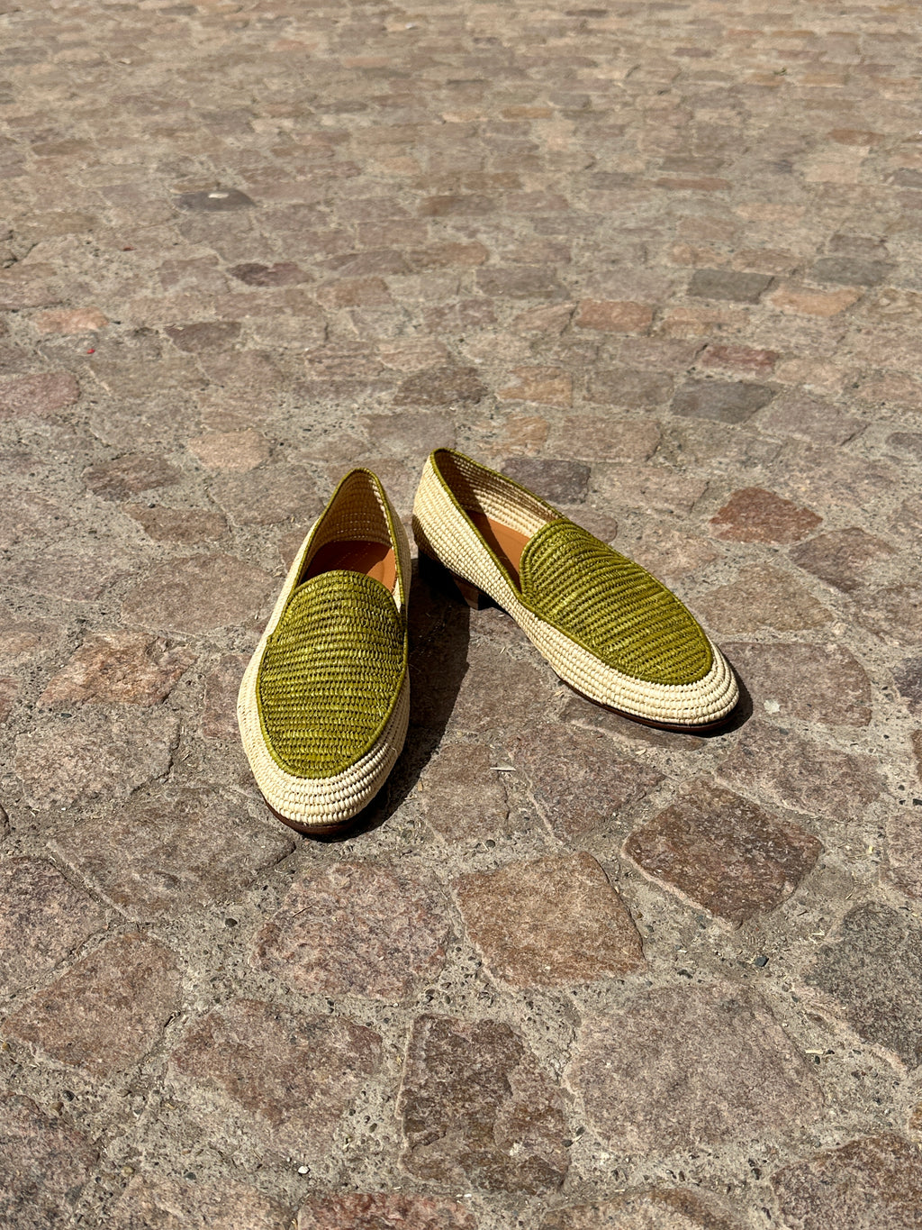 Pair of green shoes on a stone pavement