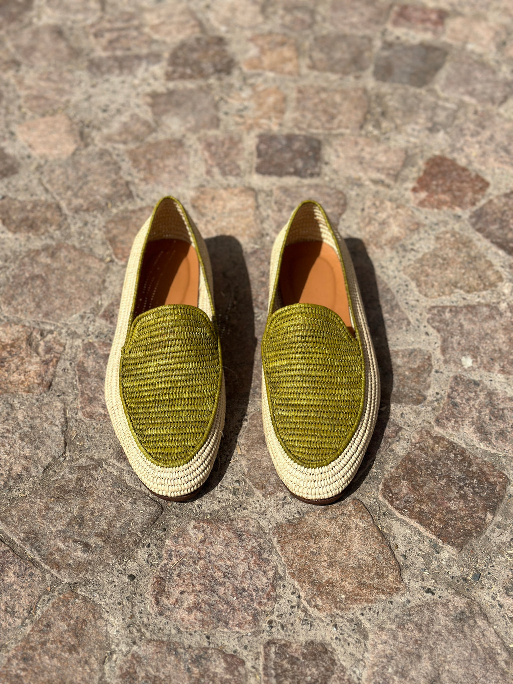 Pair of green textured shoes on a stone pavement