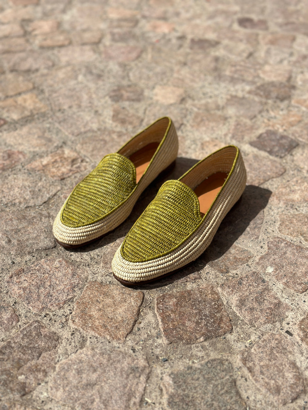 Pair of green loafers on a stone pavement
