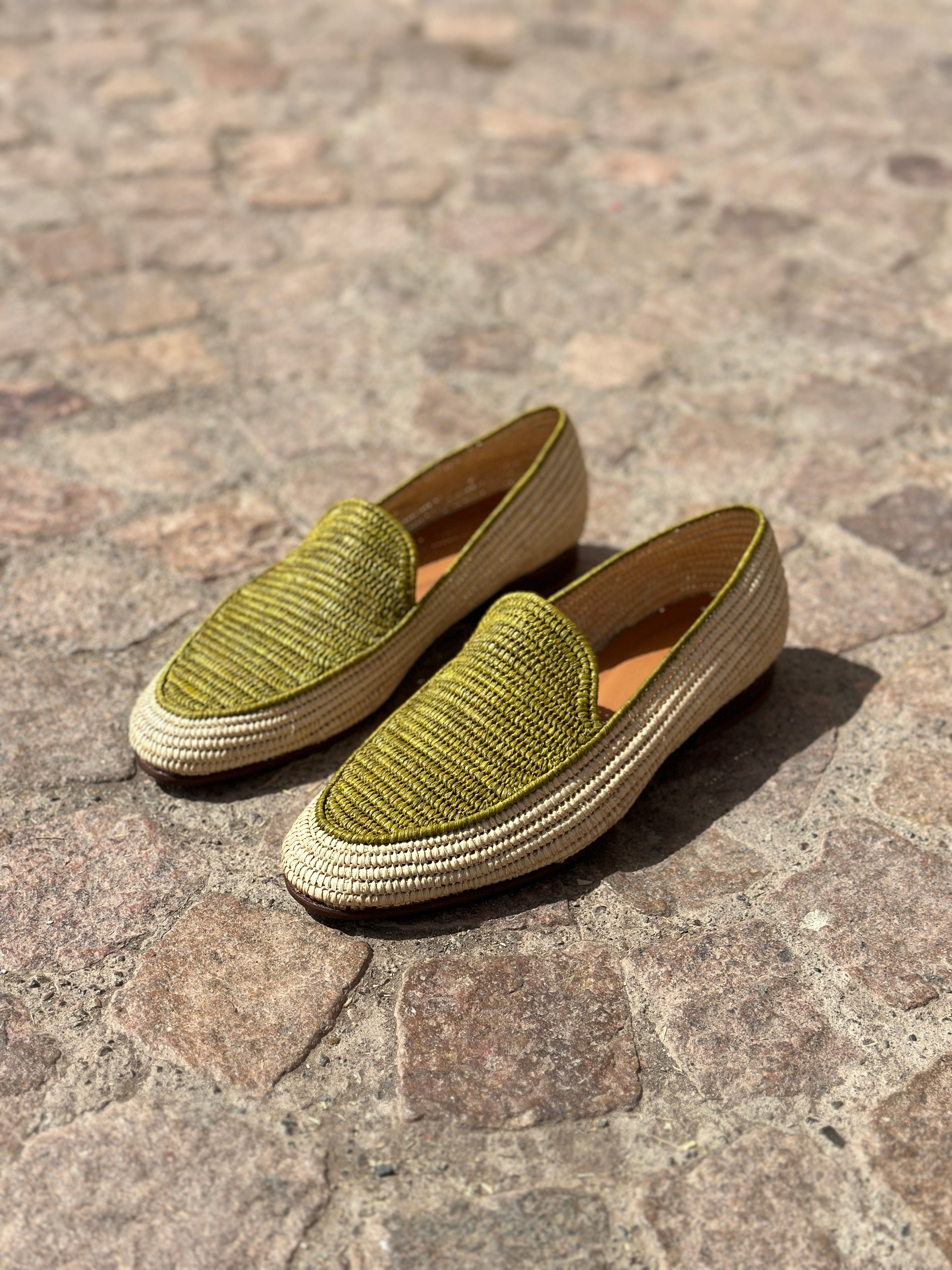 Pair of green textured loafers on a stone pavement