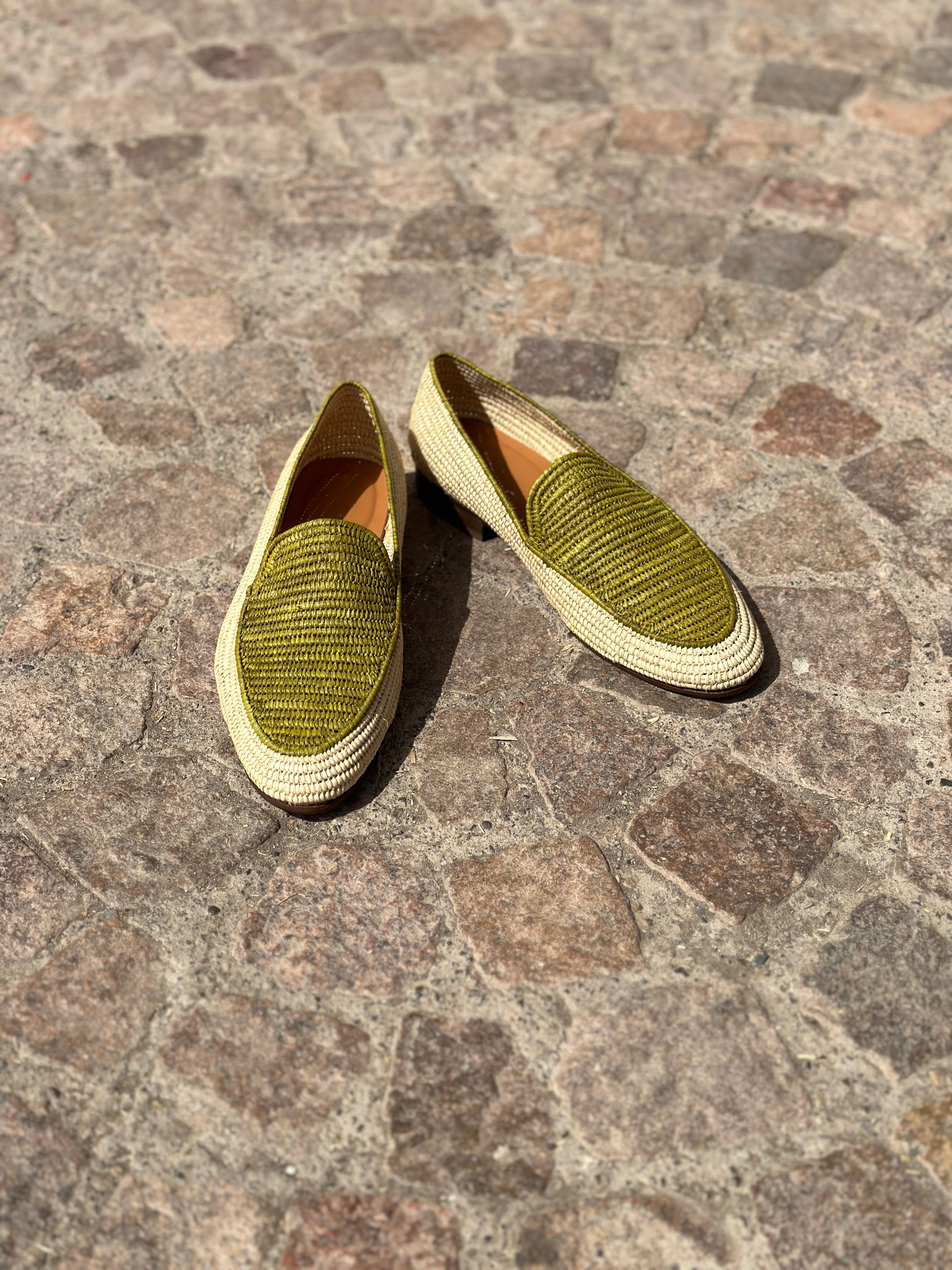 Pair of green textured loafers on a stone pavement