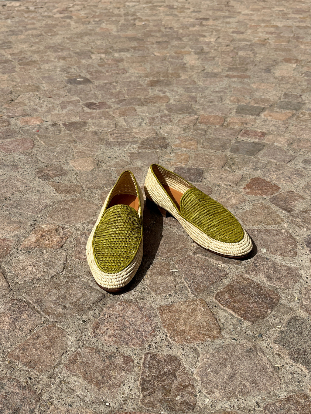 Pair of green shoes on a stone pavement