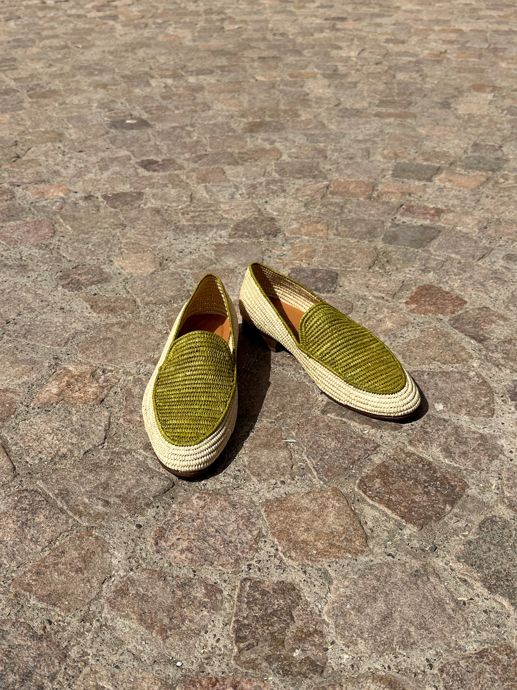 Pair of green shoes on a stone pavement