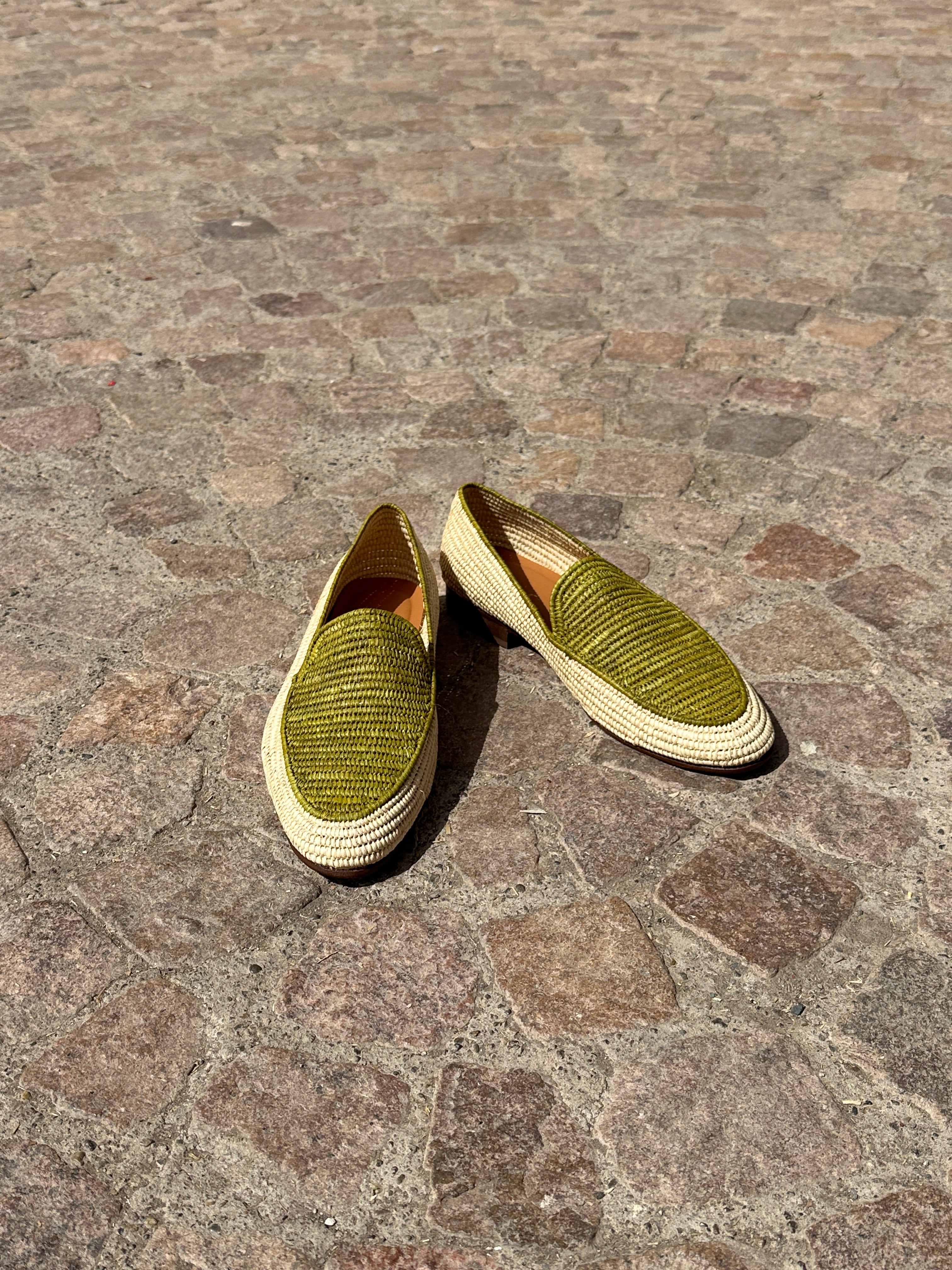 Pair of green shoes on a stone pavement