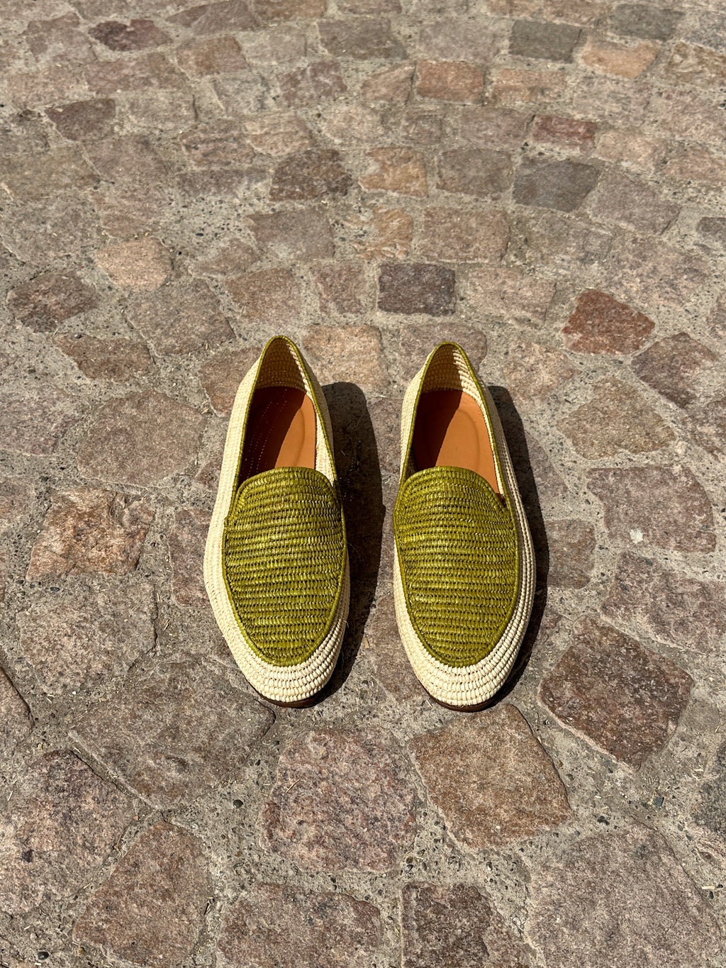 Pair of green loafers on a stone pavement