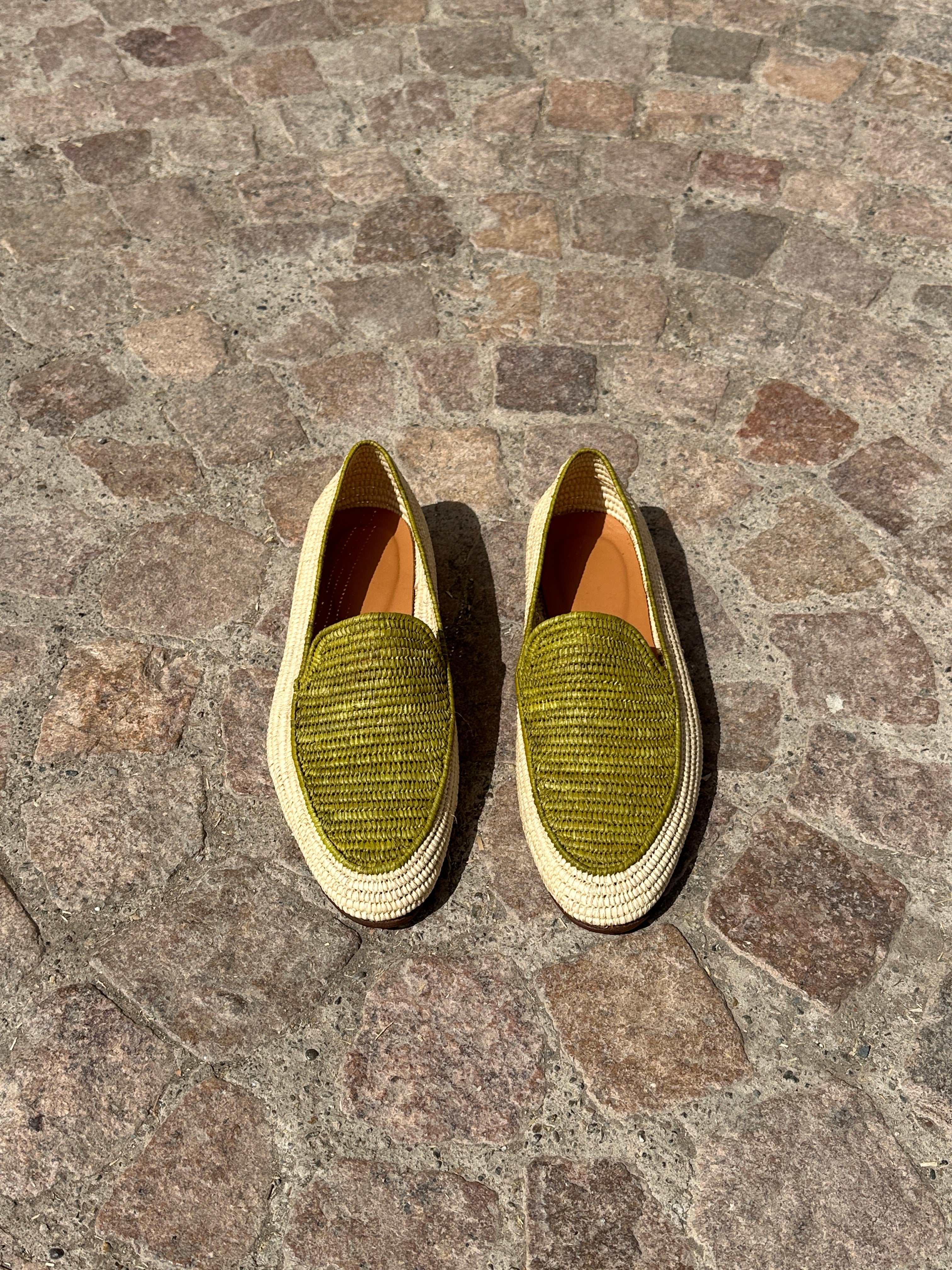 Pair of green loafers on a stone pavement
