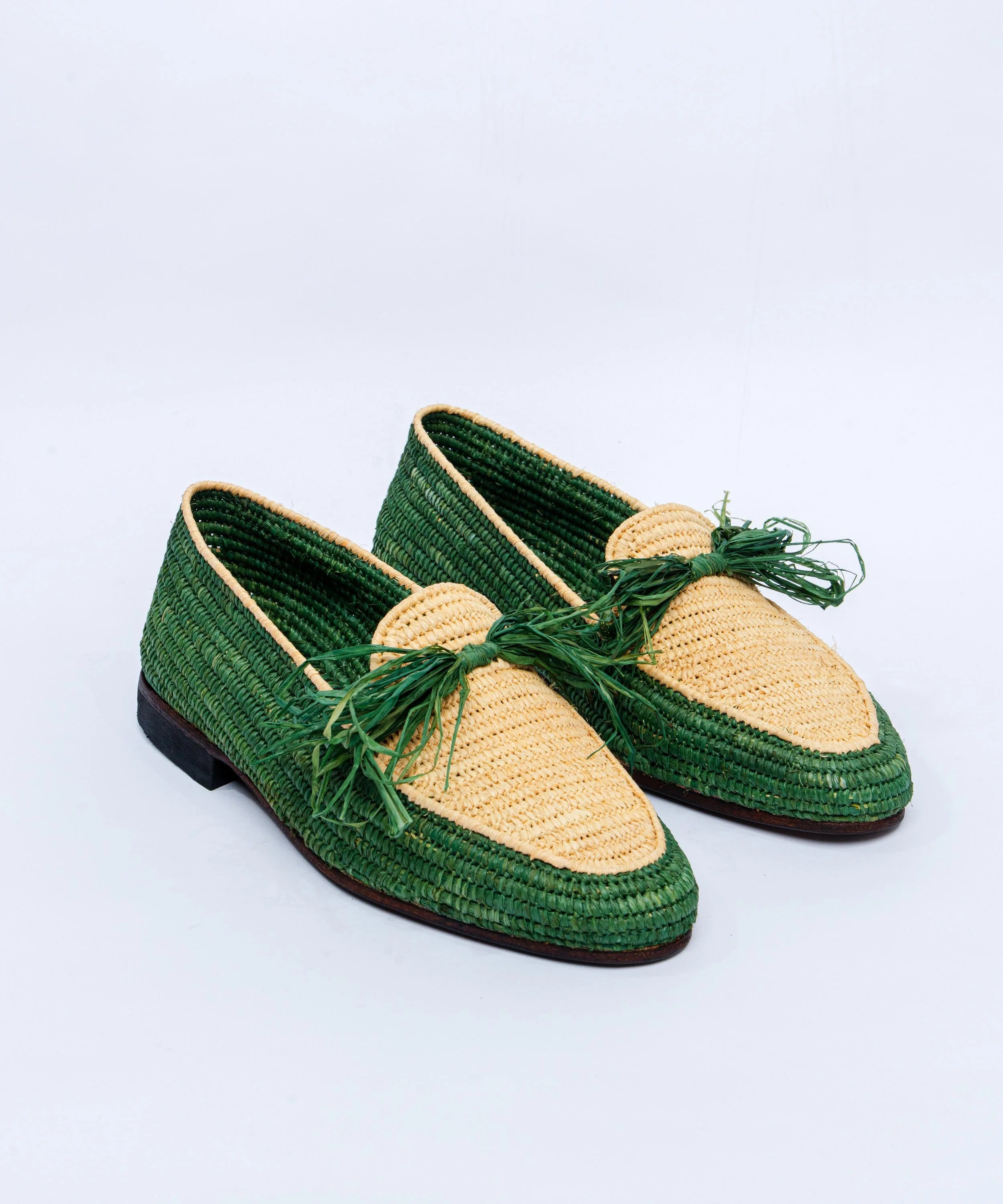 Green and beige woven shoes on a light gray background