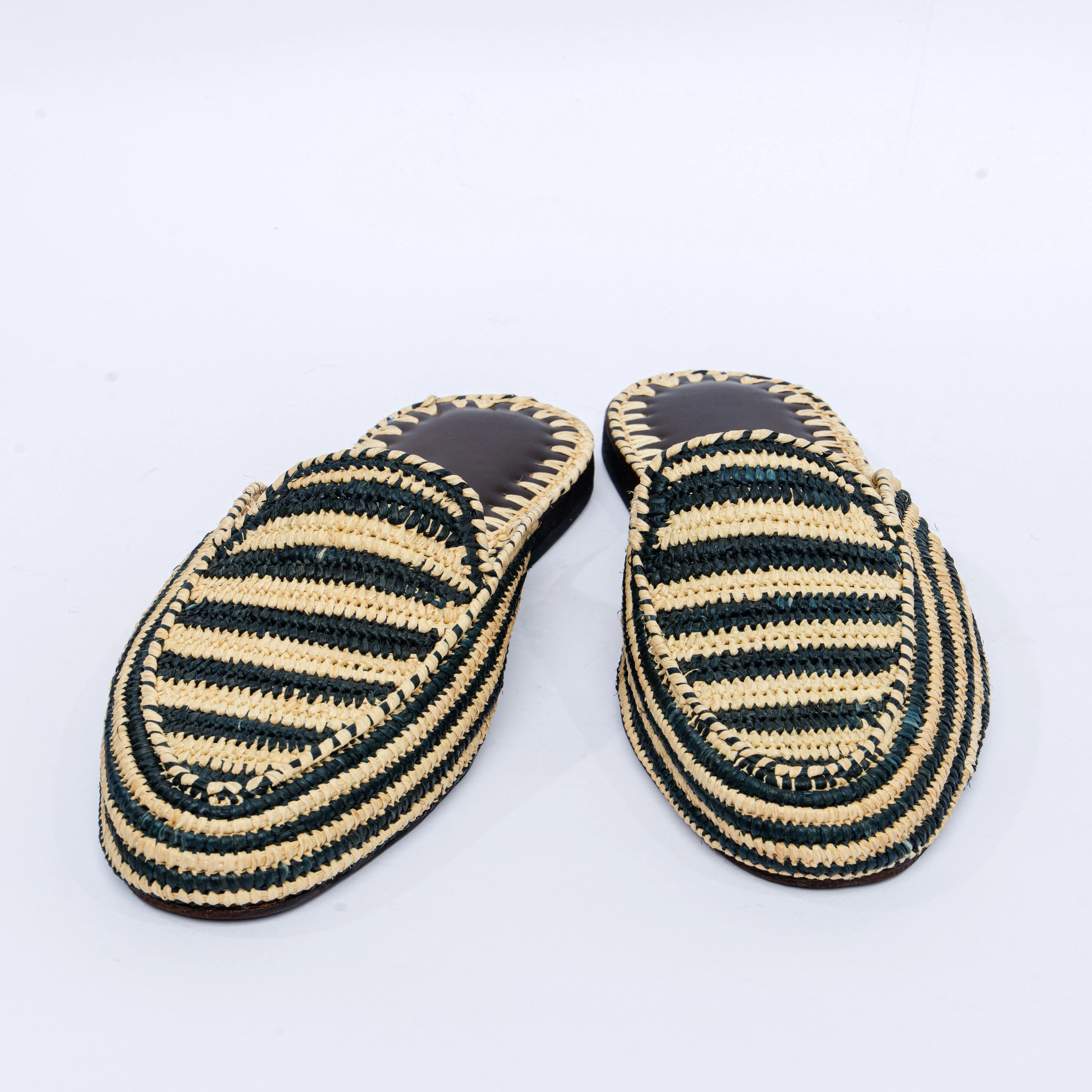 Pair of black and beige striped slippers on a white background