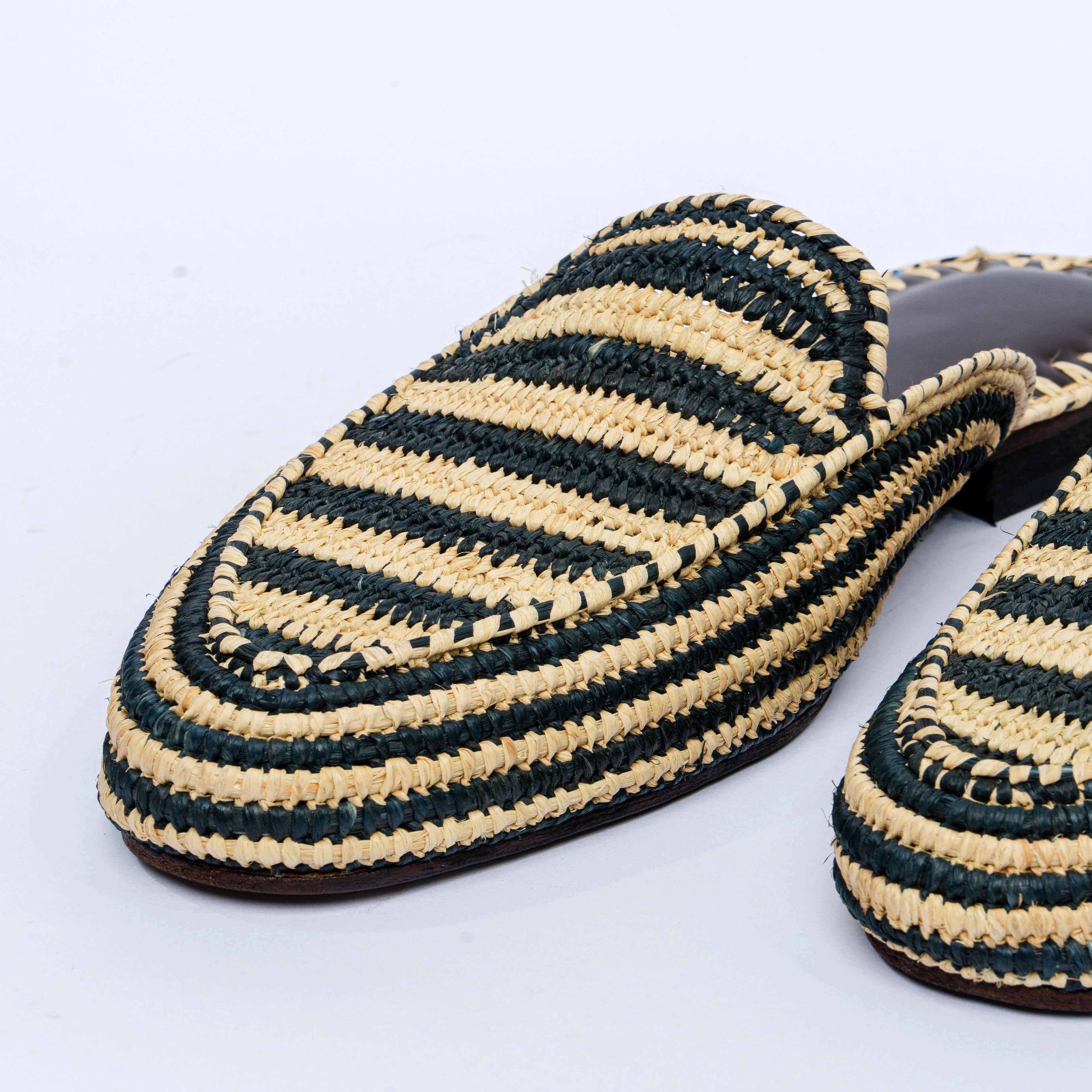 Pair of black and beige striped slippers on a light gray background