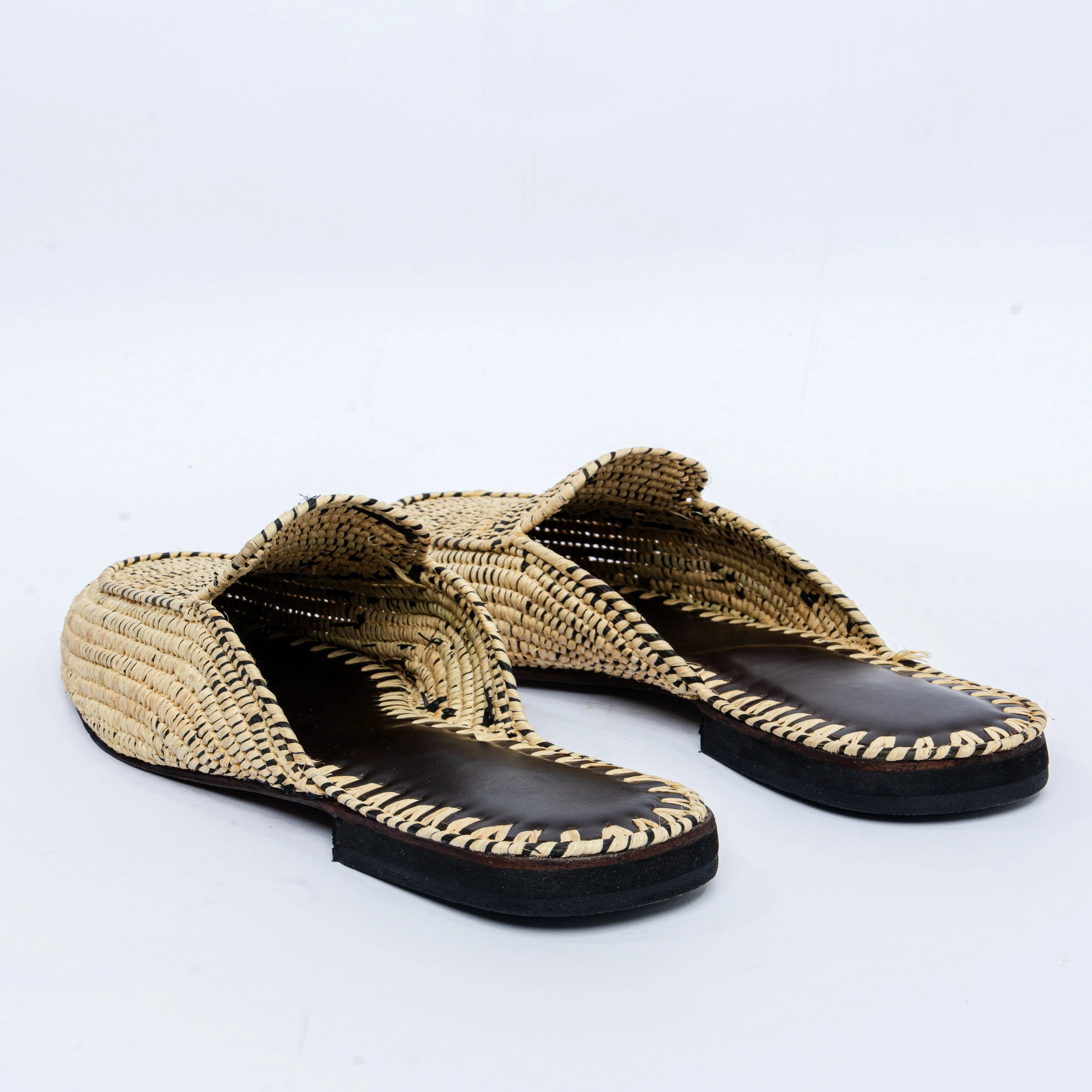 Pair of woven sandals with black soles on a light gray background