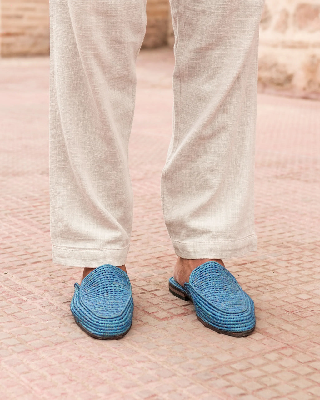 Person wearing blue slippers on a textured pink surface