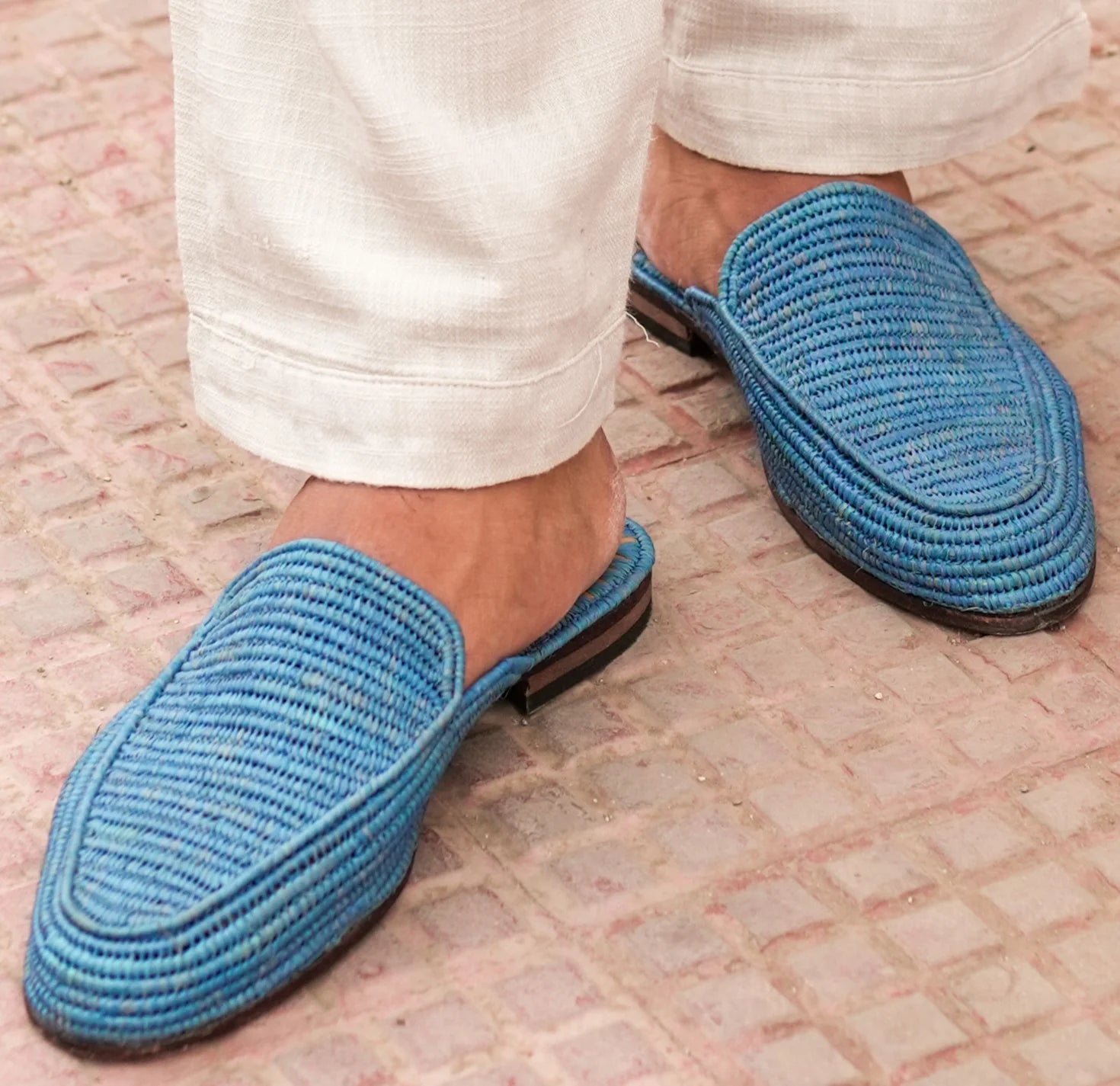Blue woven slippers worn on a stone pavement