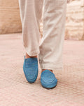 Person wearing blue slippers on a textured surface with a blurred background