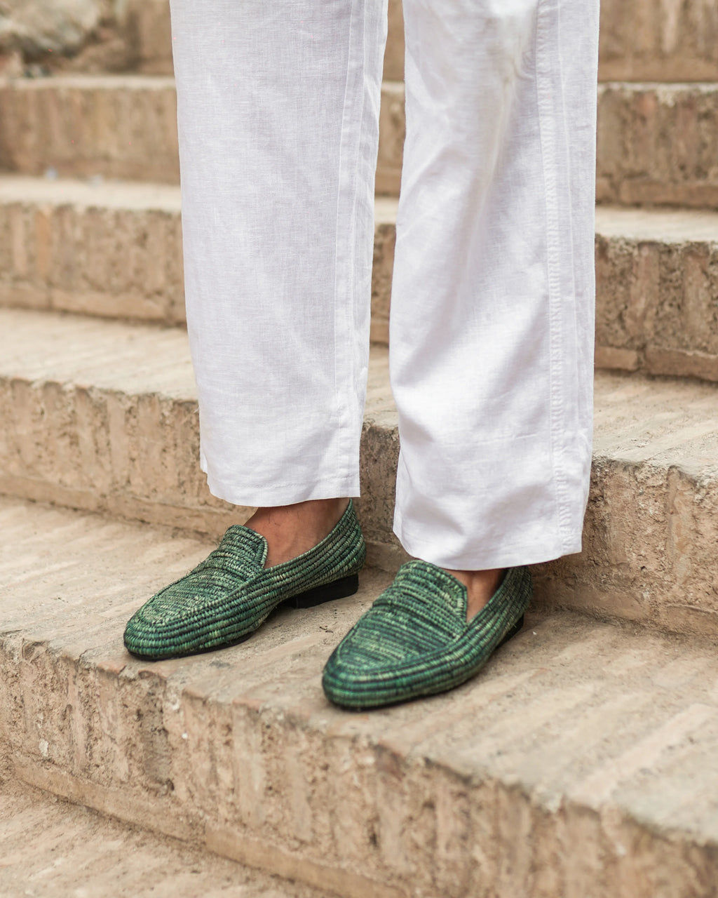 Green loafers worn with white pants on stone steps