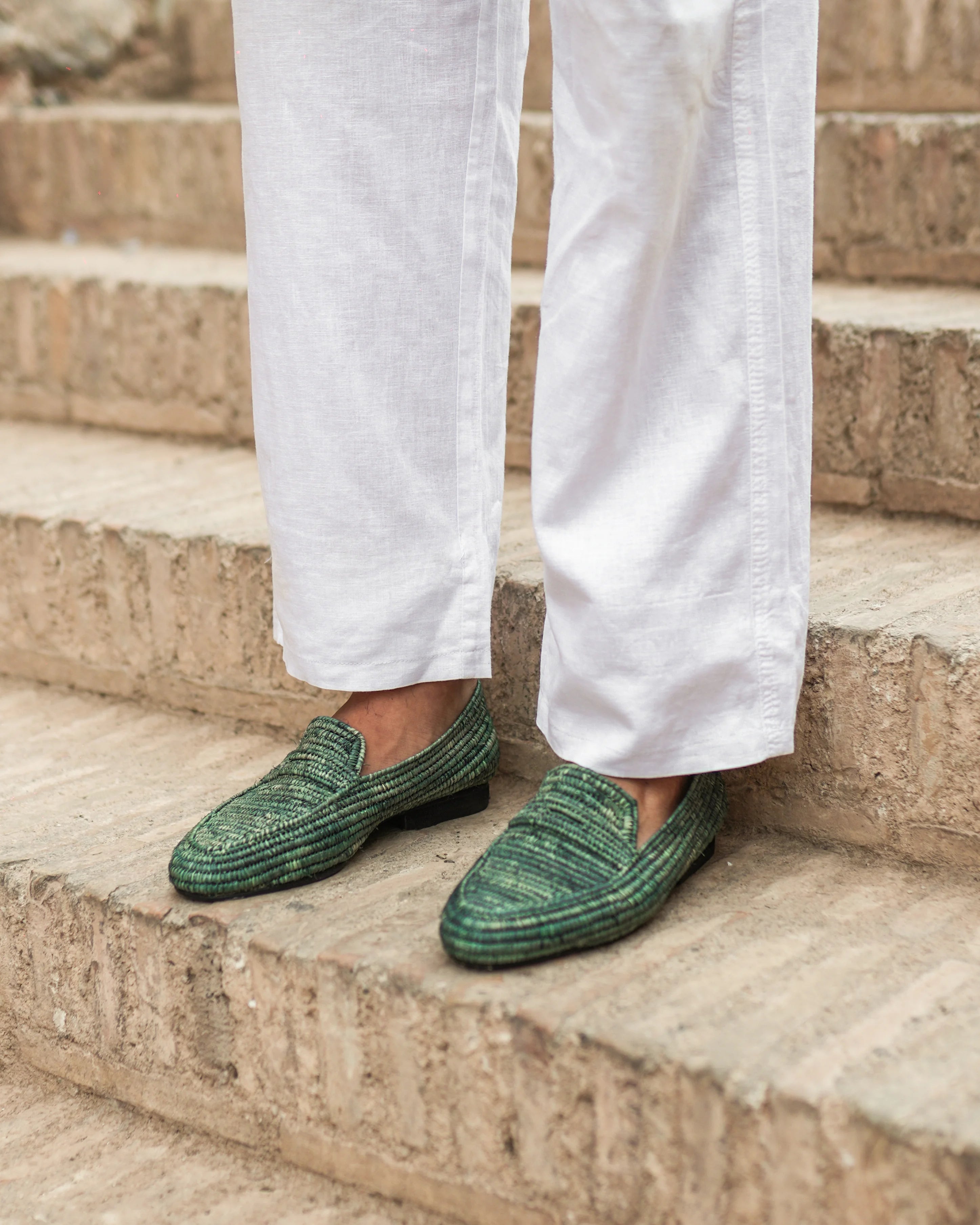 Green loafers worn with white pants on stone steps
