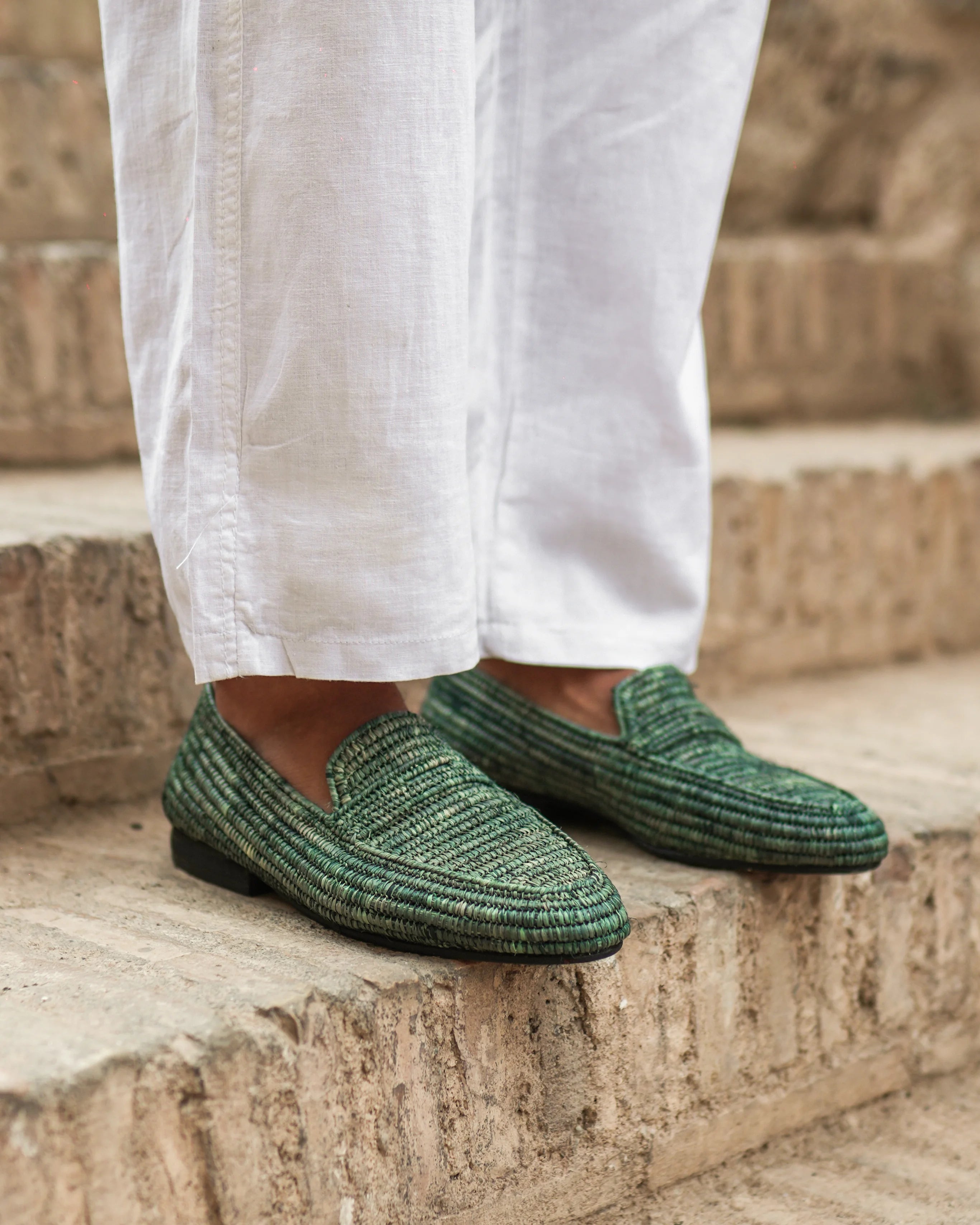 Green loafers worn with white pants on stone steps