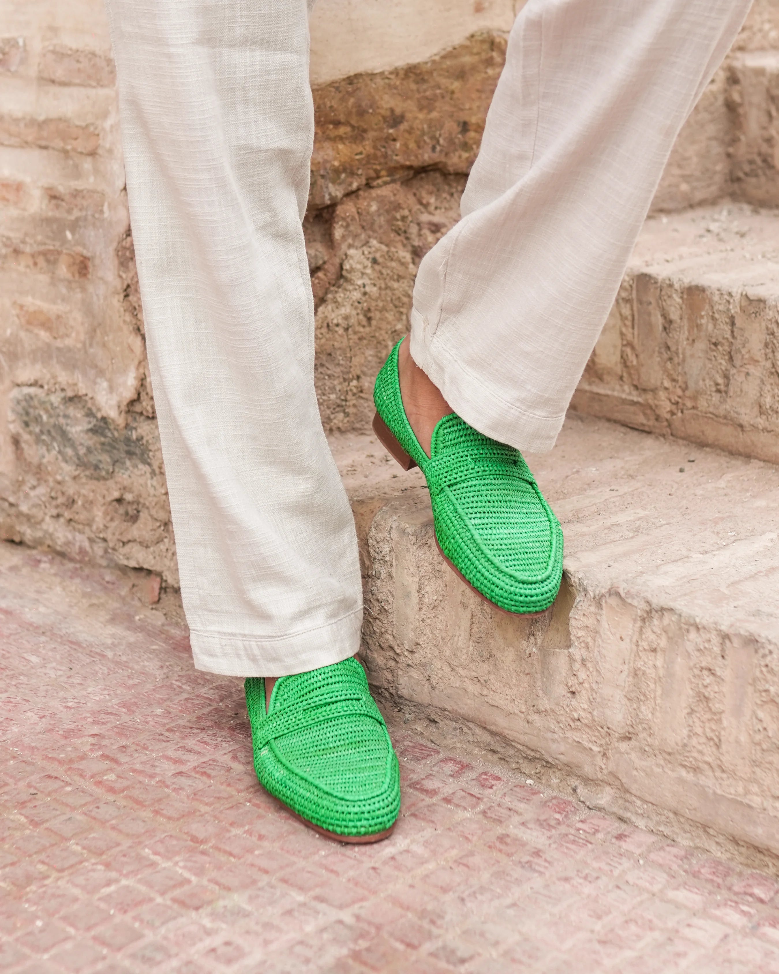 Green shoes worn with light-colored pants on stone steps.