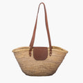 Woven basket bag with brown leather handle and flap on a white background