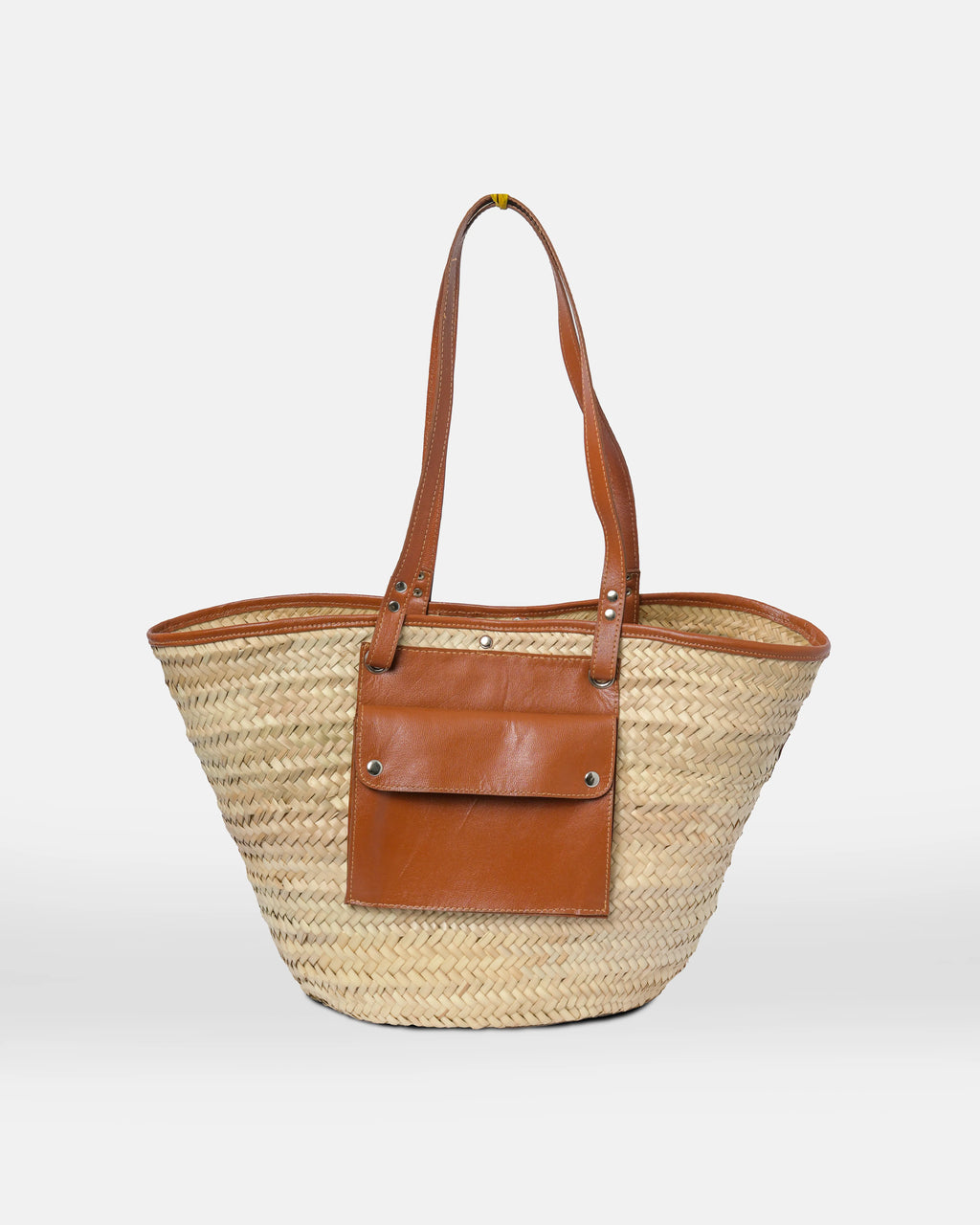 Woven straw tote bag with brown leather accents on a white background
