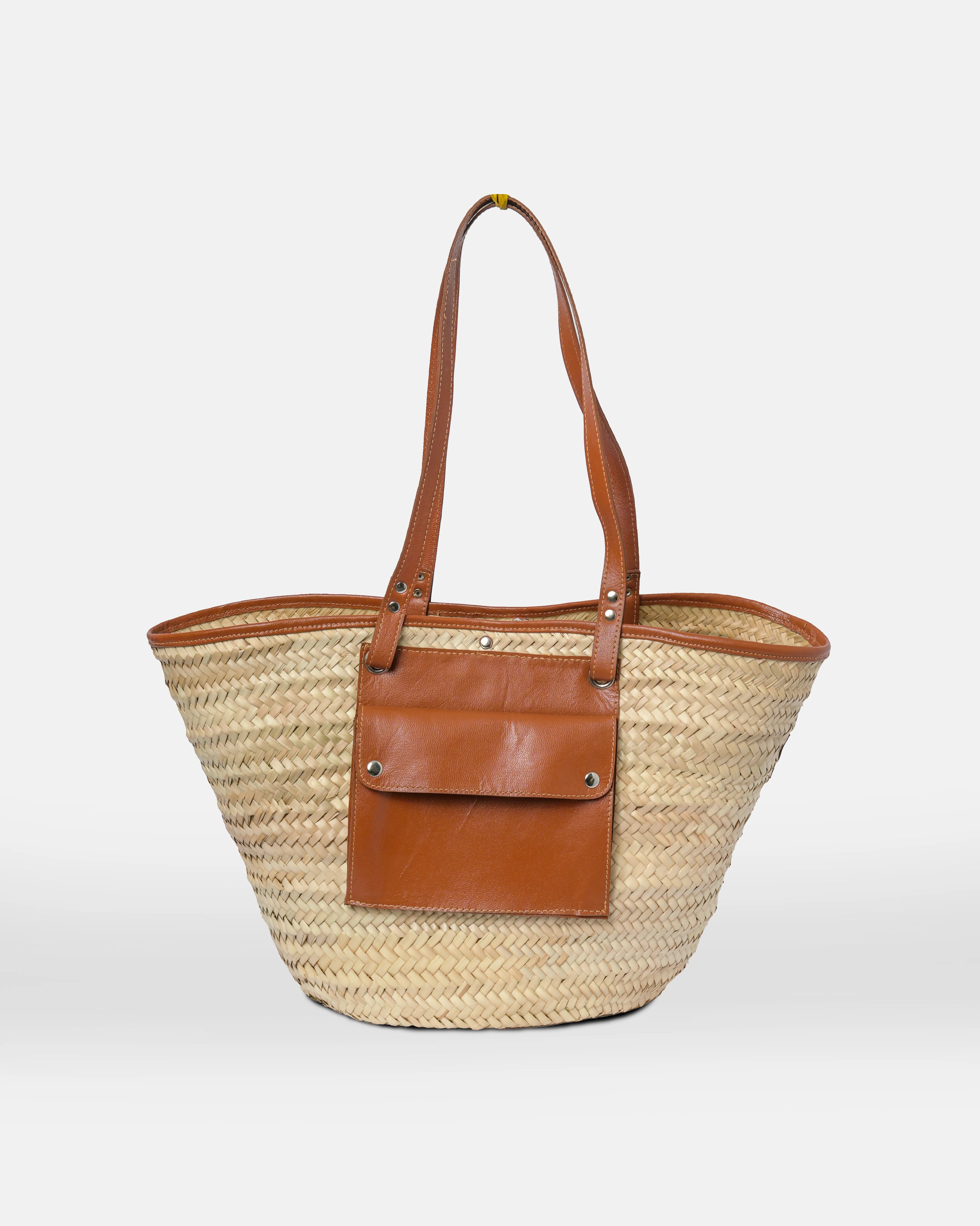 Woven straw tote bag with brown leather accents on a white background