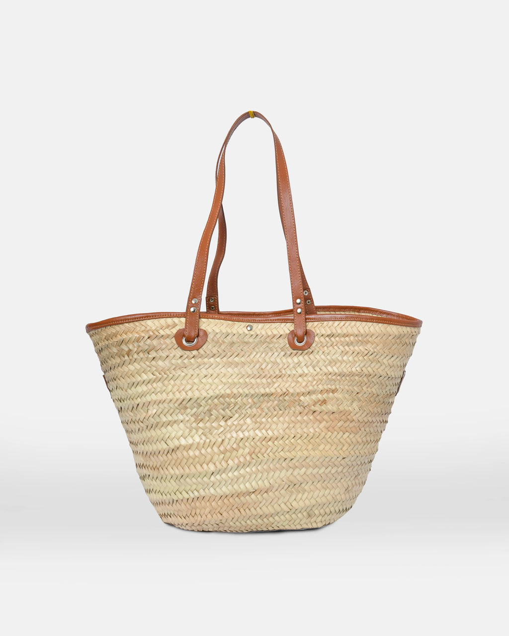 Woven straw tote bag with brown leather handles on a white background