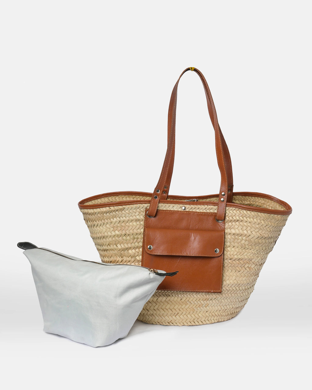 Woven straw tote bag with brown leather straps on a white background
