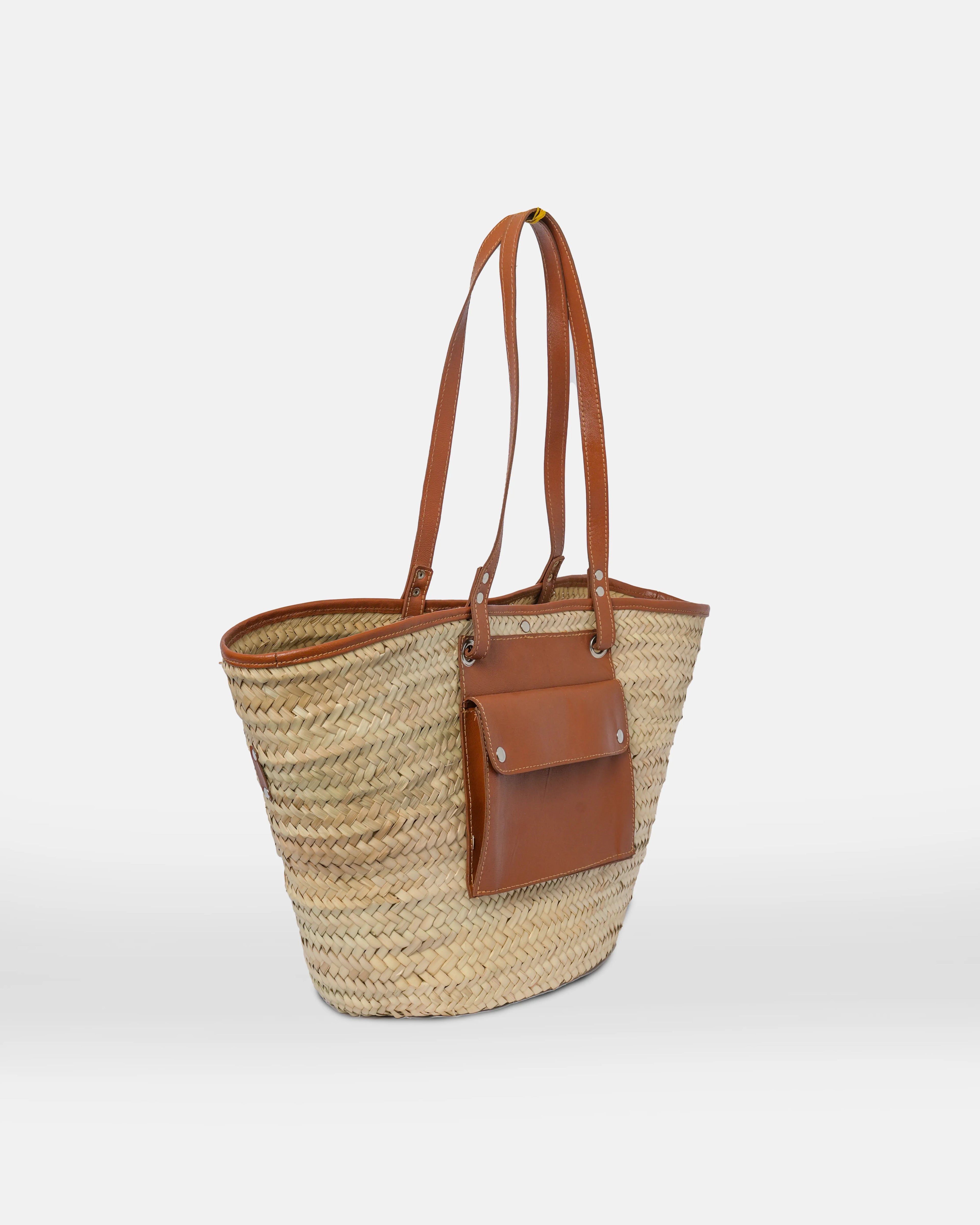 Woven straw tote bag with brown leather accents on a white background
