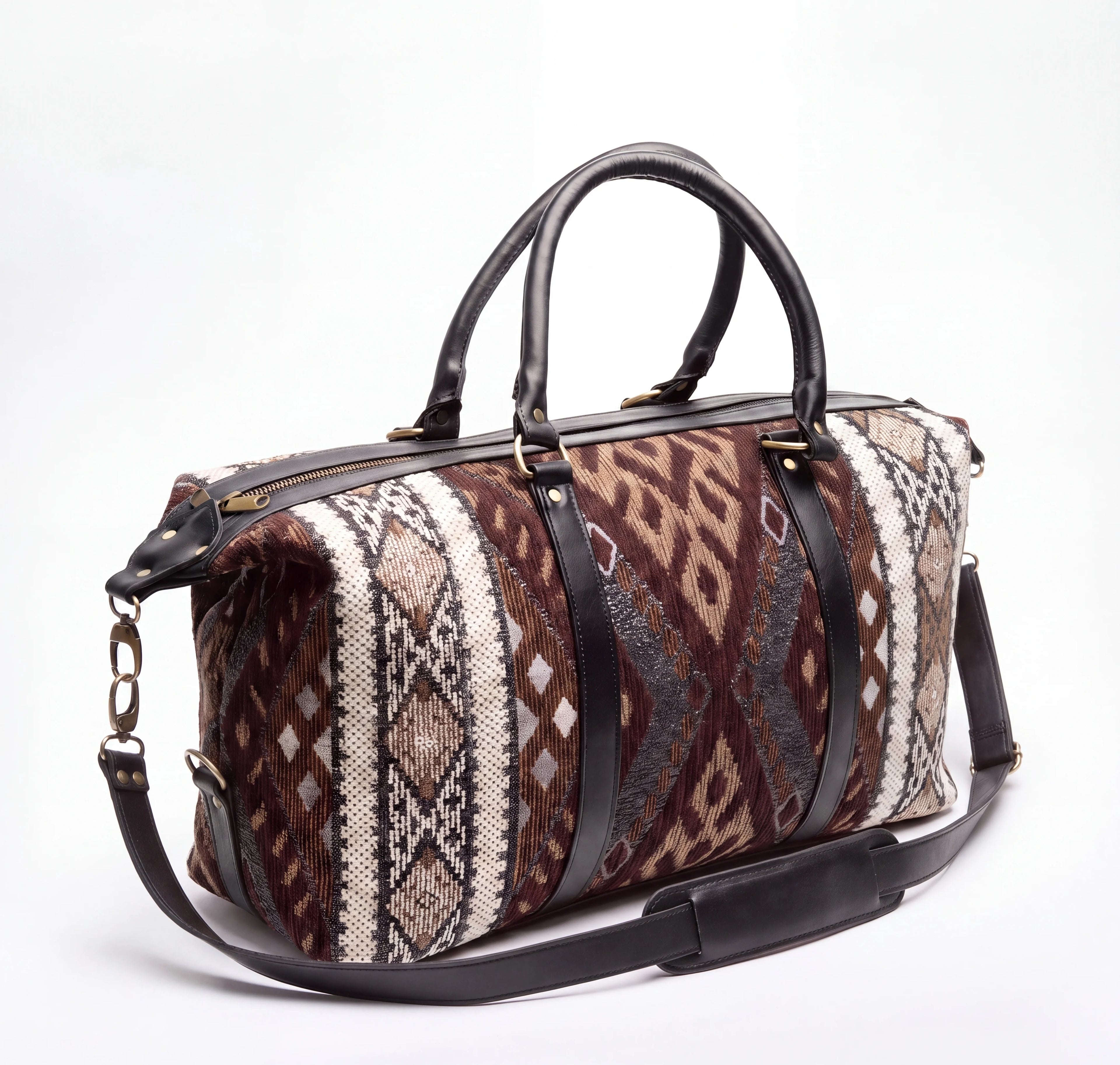 A duffel bag with a brown, beige, and gray geometric patterned fabric body, black leather handles and shoulder strap, and gold-tone hardware, photographed on a white background.