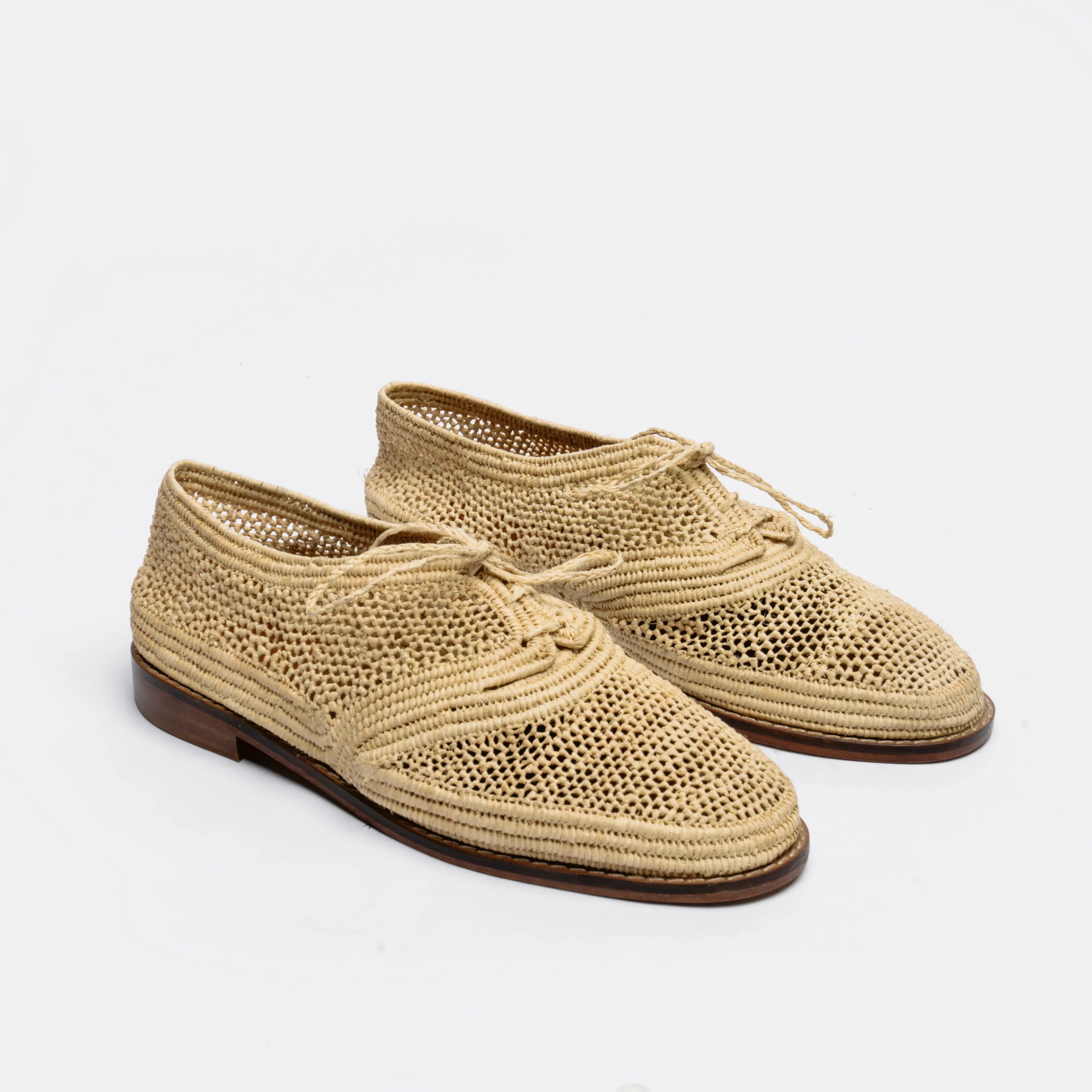 A pair of woven straw lace-up shoes with a brown sole, photographed on a clean white background.