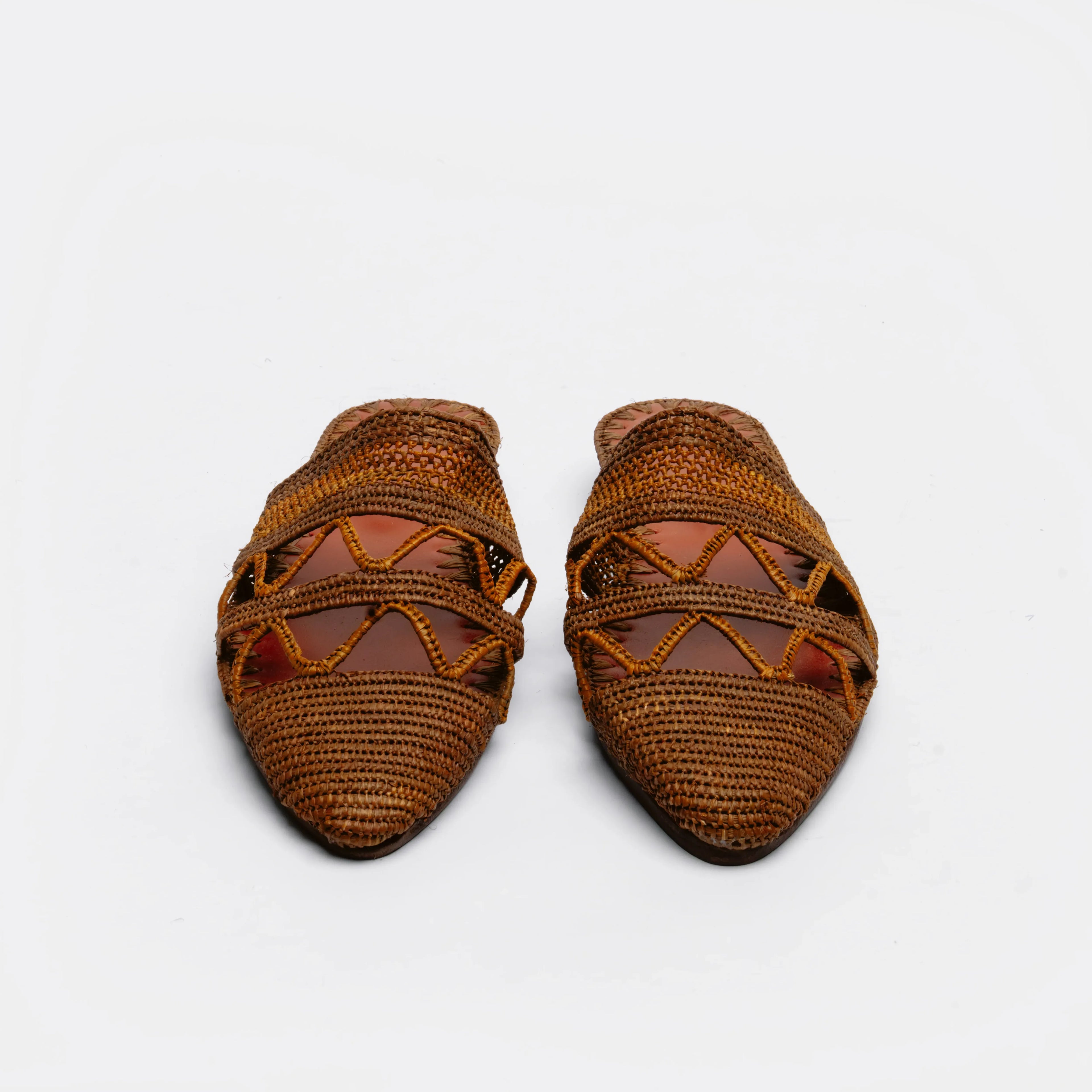A pair of brown woven raffia mule sandals with criss-cross woven straps, shown on a plain white background.