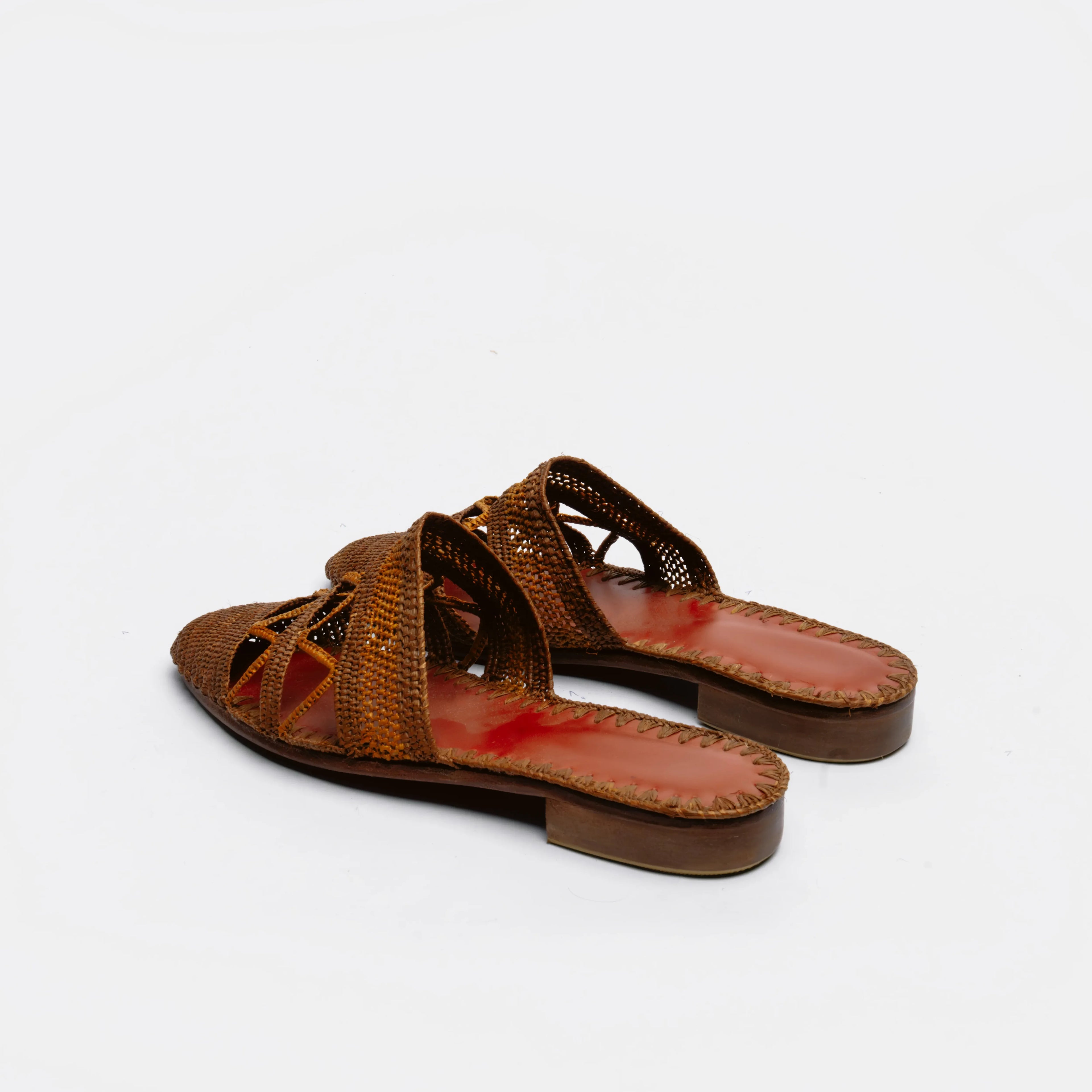 A pair of women's flat slide sandals with woven brown straps and a reddish-brown footbed, shown from a side angle on a white background.