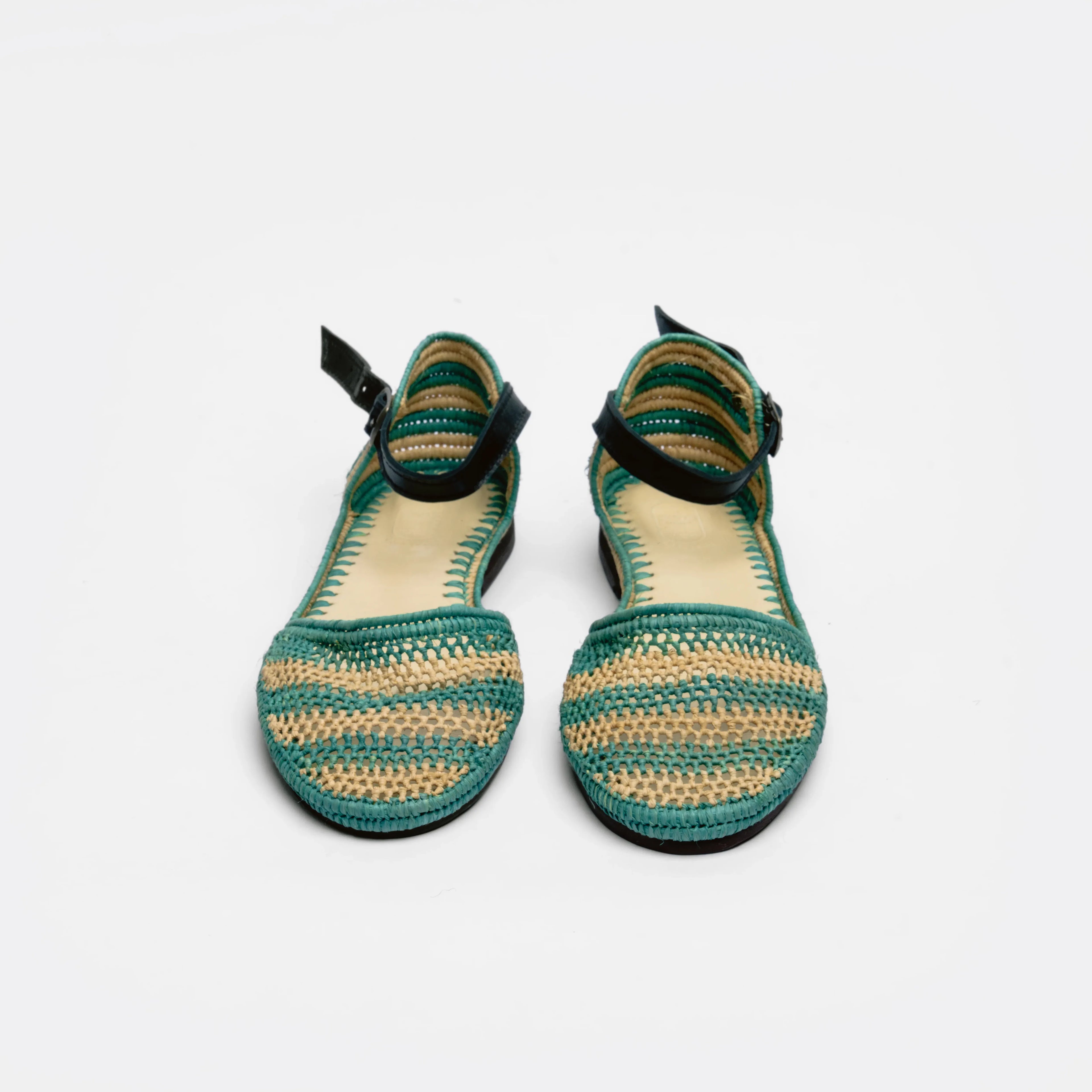 A pair of women's flat sandals with woven green and beige striped uppers, black ankle straps, and a low block heel, shown against a plain white background.