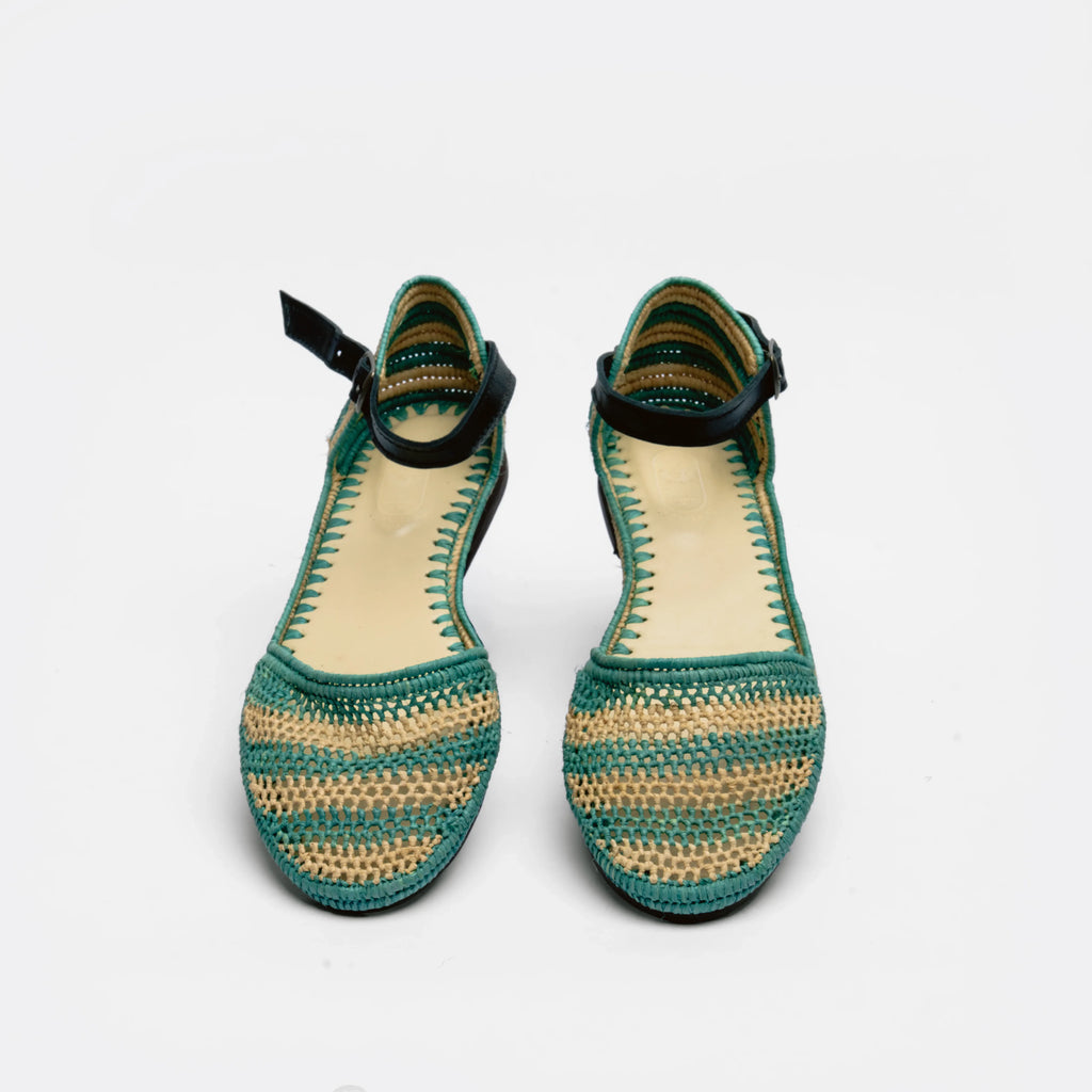 A pair of women's crochet flat sandals with a green and beige woven pattern, black ankle straps, and a light beige insole, shown against a plain white background.
