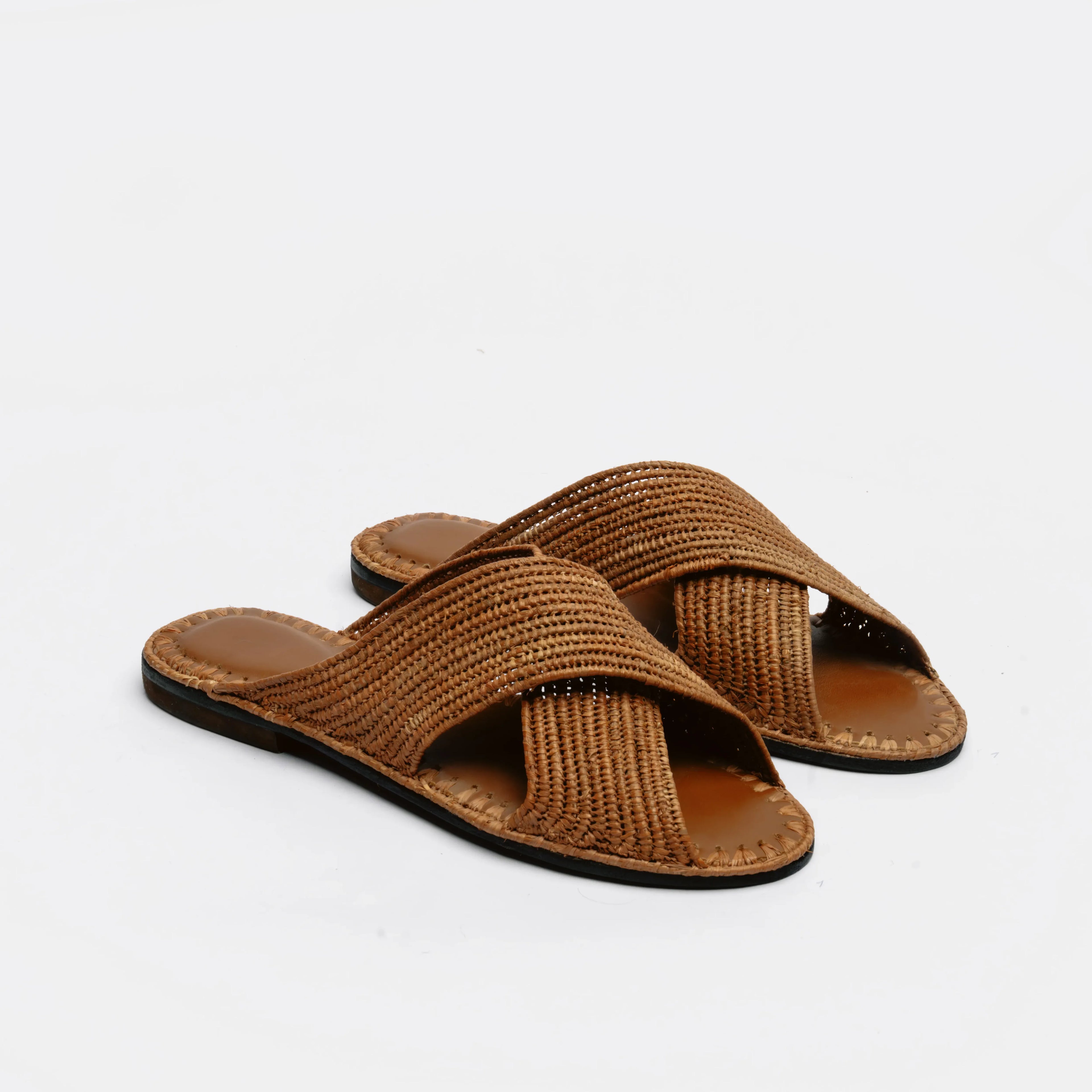 A pair of brown woven slide sandals with crisscrossing straps and dark soles, displayed on a clean white background.