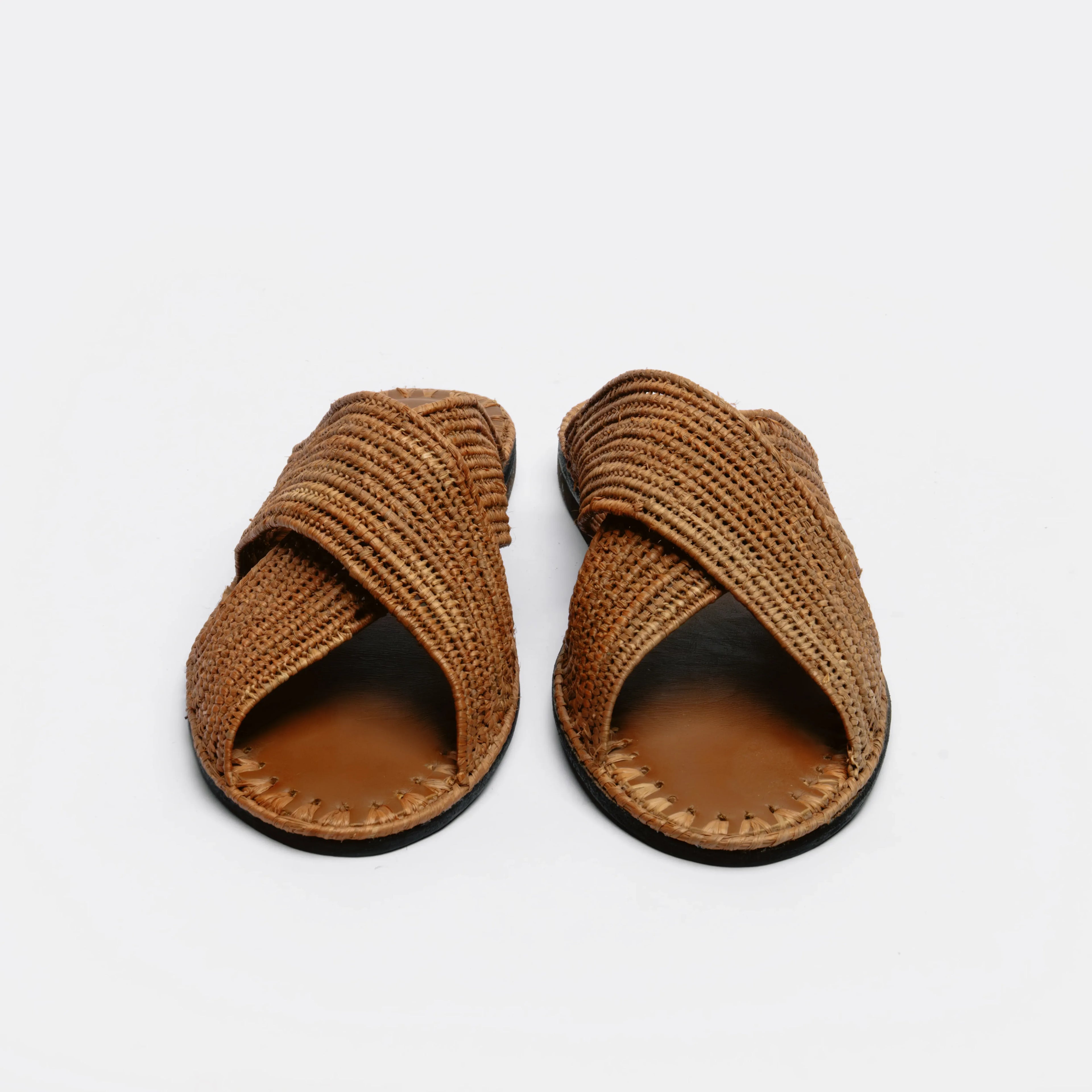 A pair of brown woven slide sandals with crisscrossing straps and a tan footbed, shown from a top-down view on a light gray background.