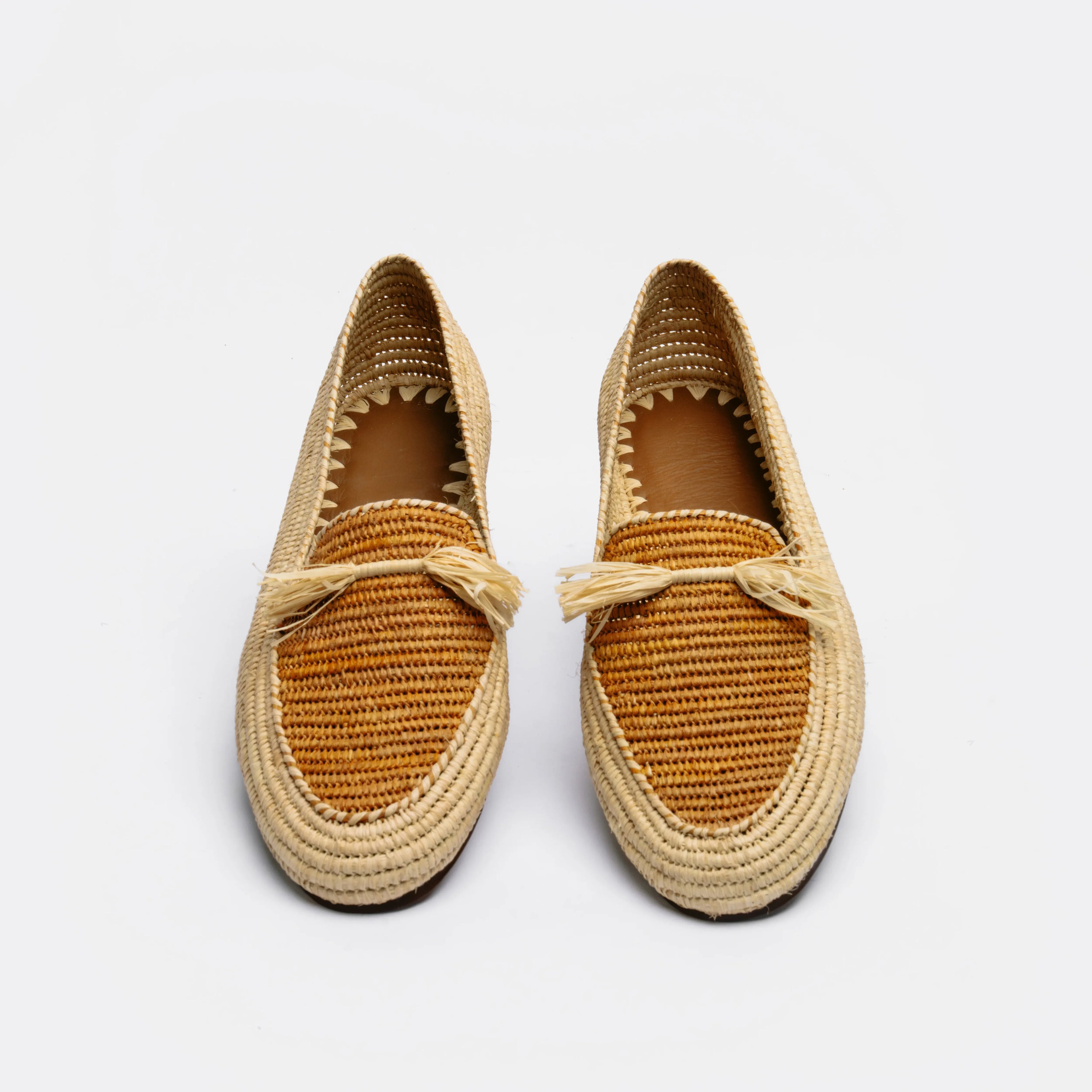 A pair of woven espadrille-style loafers in natural straw and warm tan tones, shown from above on a clean white background.